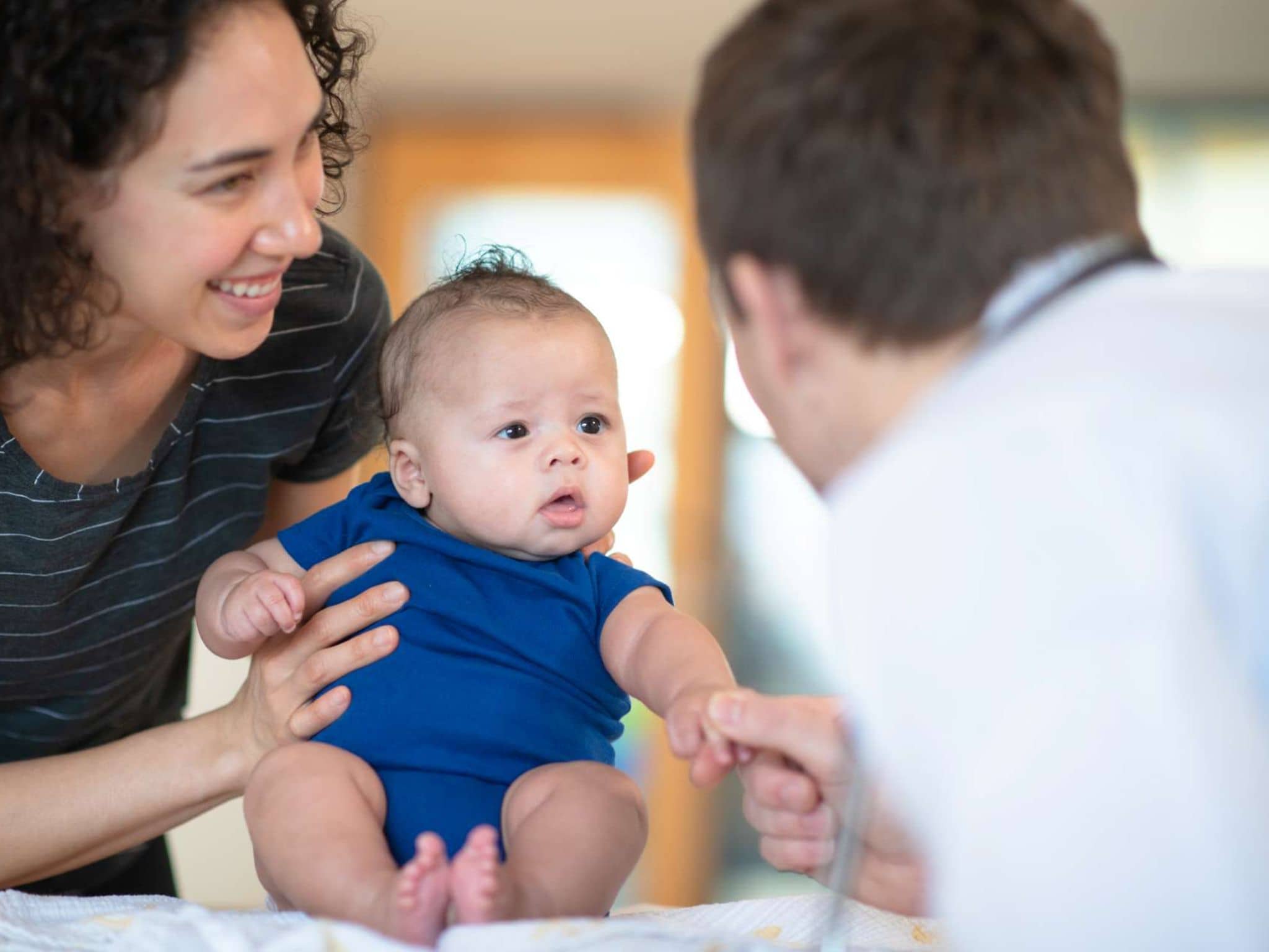 Bonusprogramm für Babys: Eine Mutter hält Ihr Baby bei einer Vorsorgeuntersuchung beim Arzt fest.