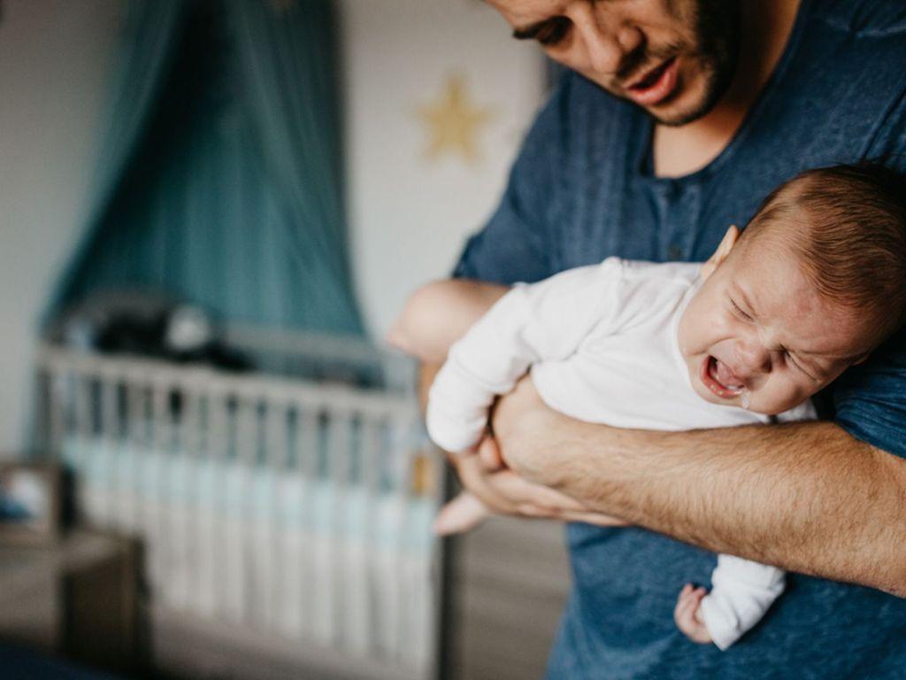 Ein Vater beruhigt sein Baby, das Magen-Darm-Probleme hat