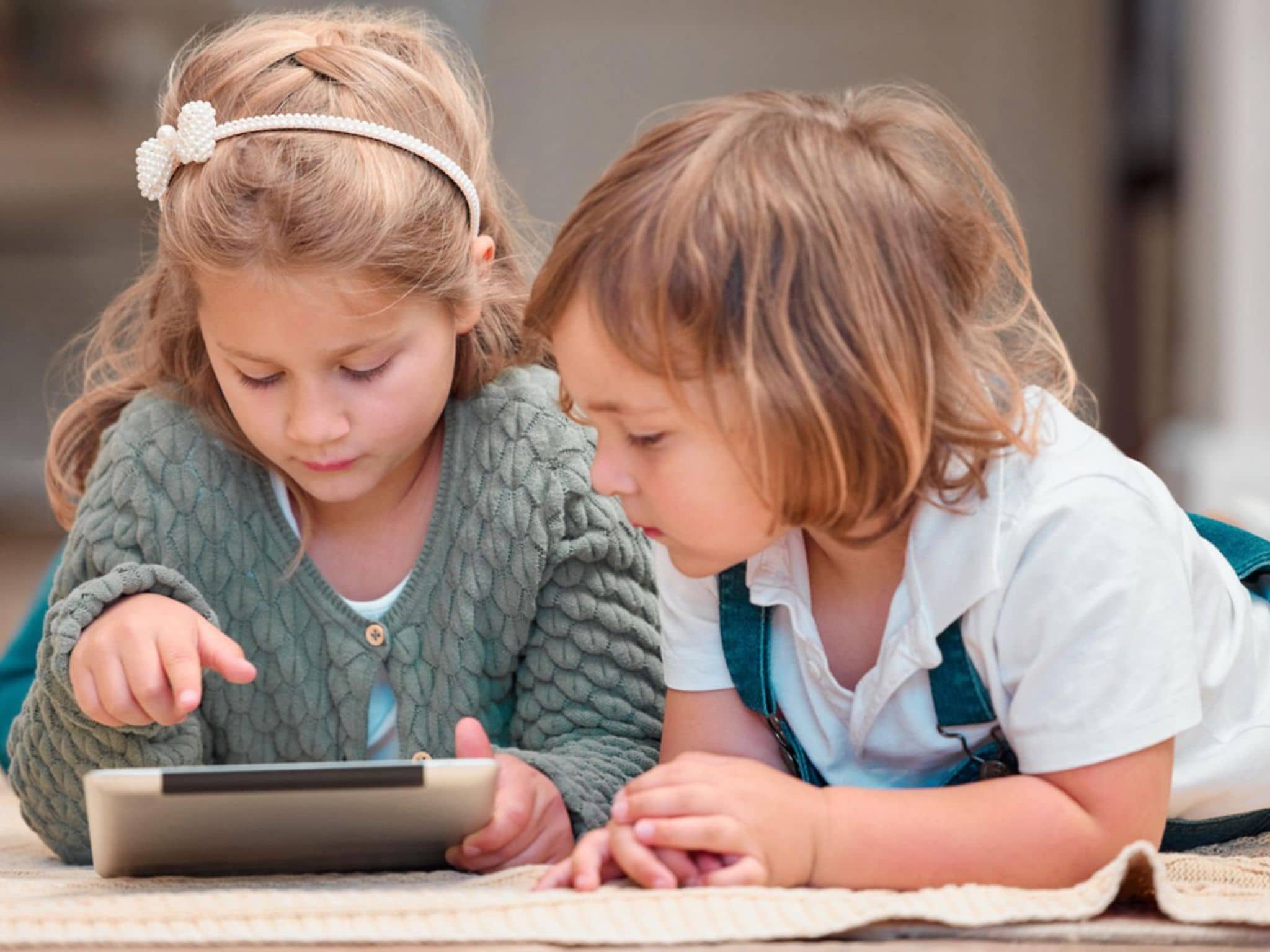 Mediensucht bei Kindern: Zwei Kleinkinder schauen auf ein Tablet