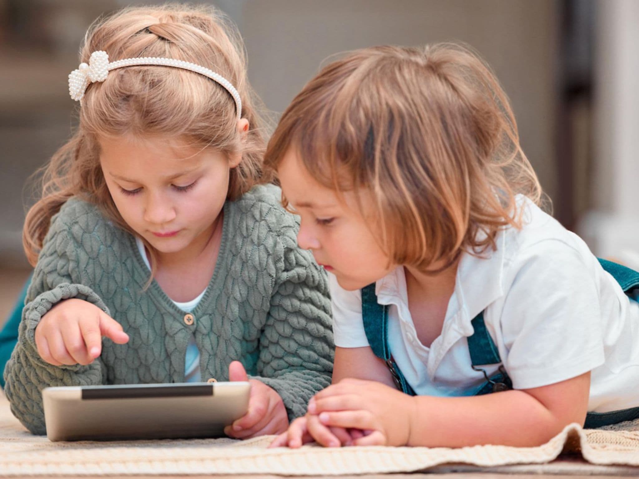 Mediensucht bei Kindern: Zwei Kleinkinder schauen auf ein Tablet