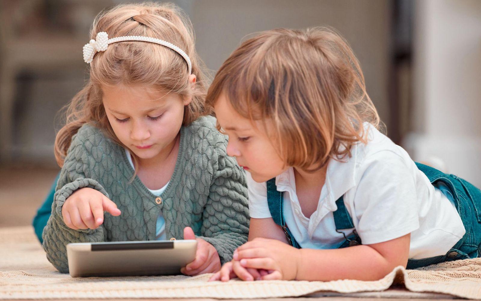 Mediensucht bei Kindern: Zwei Kleinkinder schauen auf ein Tablet