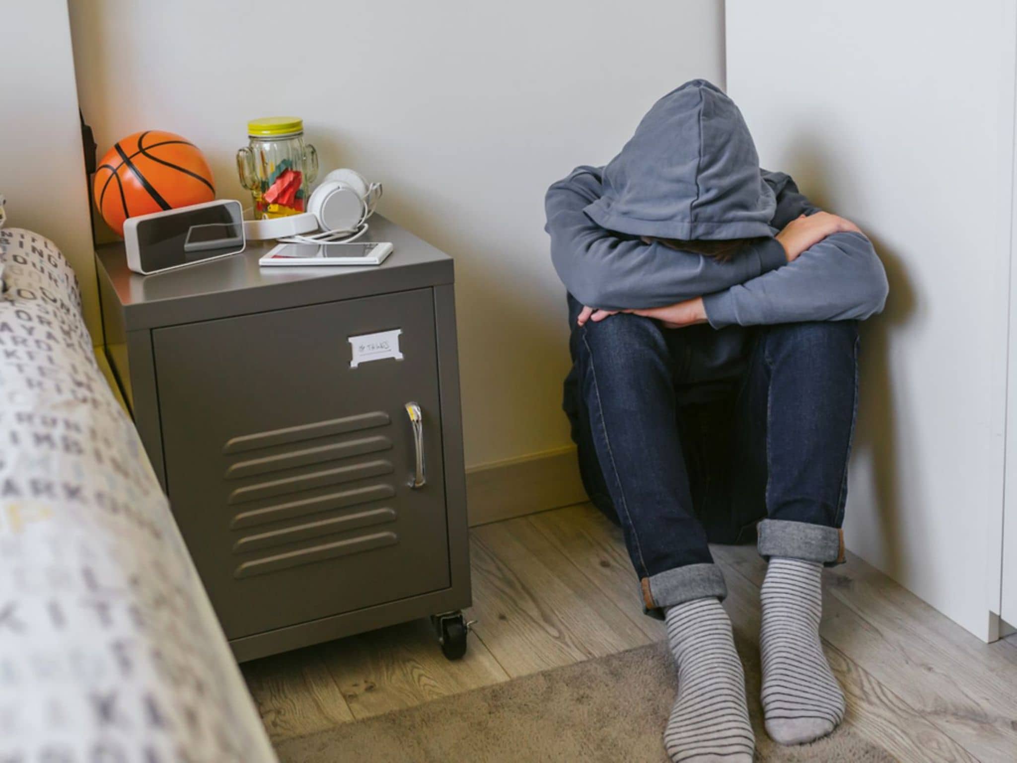 Angststörungen bei Teenagern: Ein Jugendlicher sitzt allein auf dem Fußboden