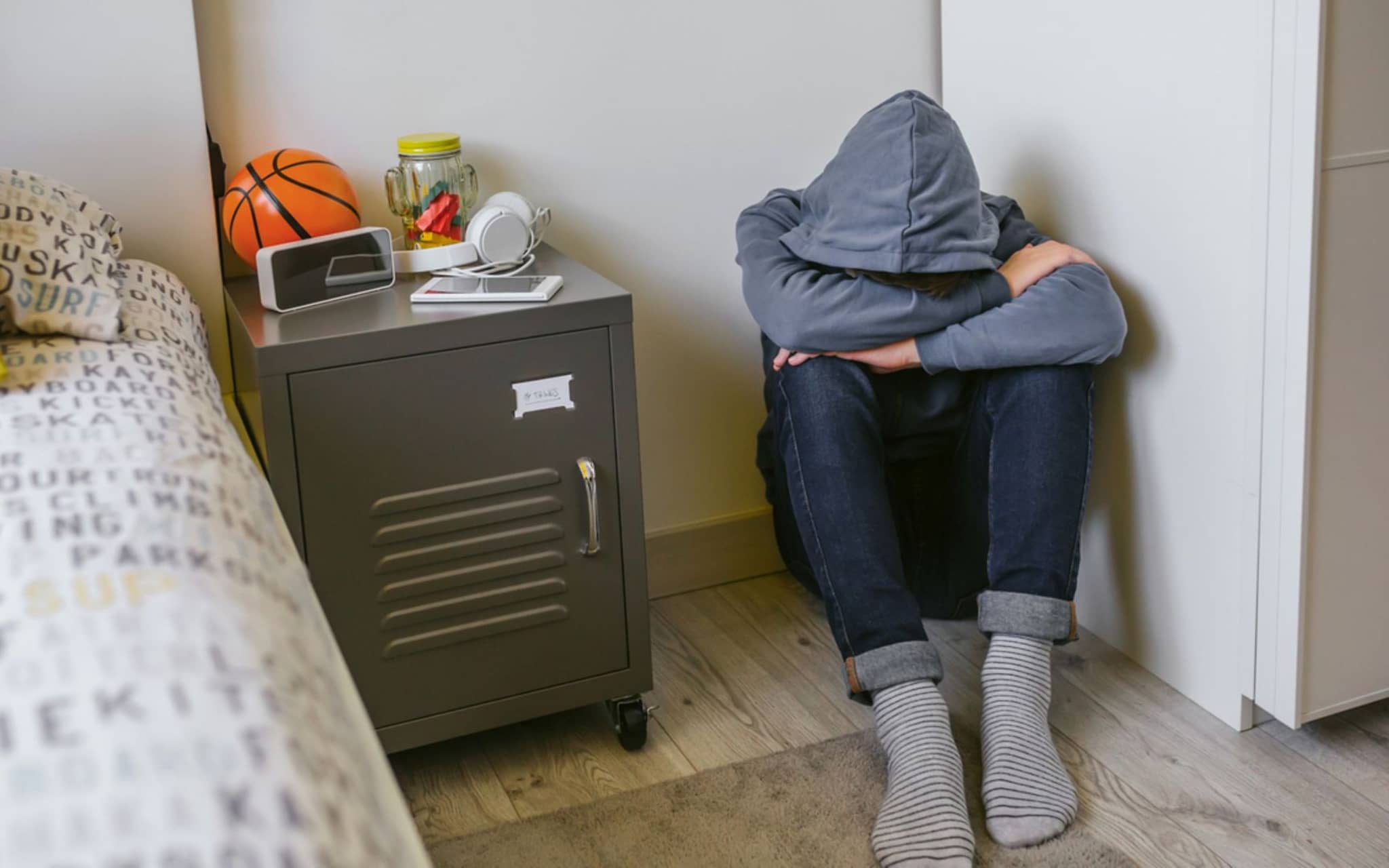 Angststörungen bei Teenagern: Ein Jugendlicher sitzt allein auf dem Fußboden