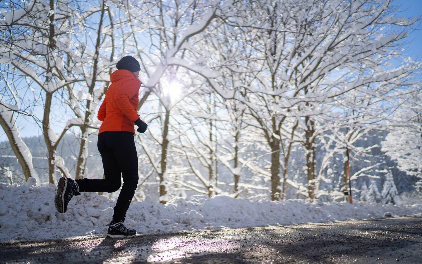 Laufen bei Kälte: Frau läuft eine verschneite Straße entlang