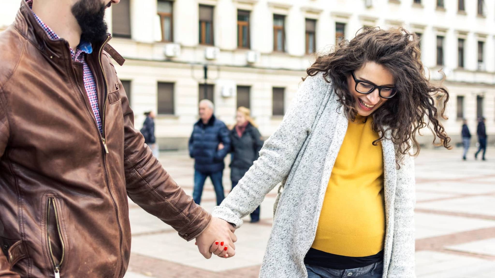 Symbolbild Geburtsvorbereitung: Paar spaziert händchenhaltend durch die Stadt
