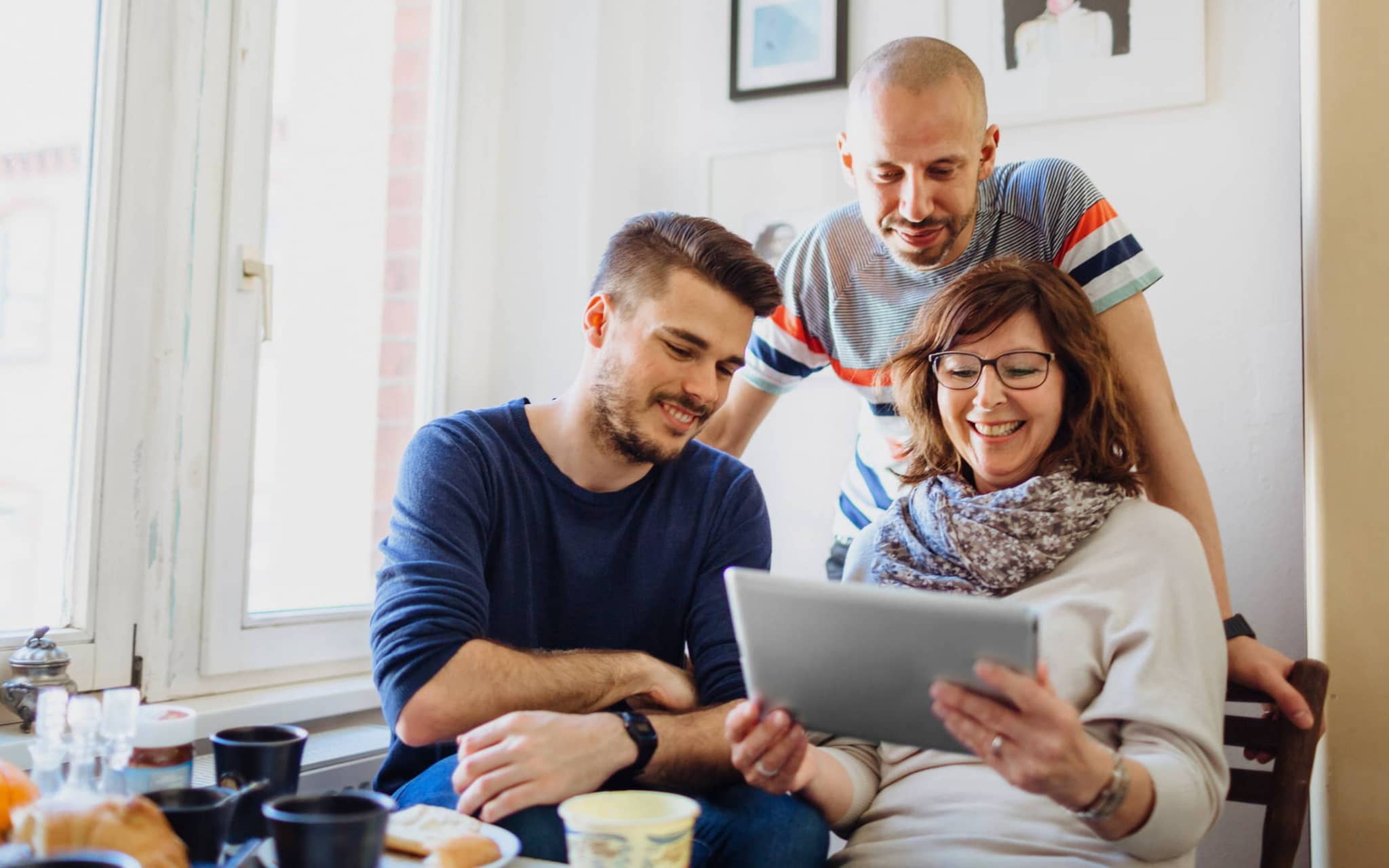 Bild: Frau und zwei Männer schauen auf ein Tablet, auf dem die Selbstlernkurse sind.