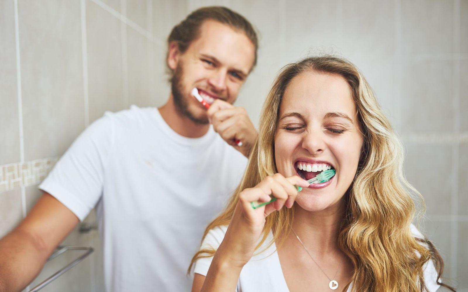 Bild: Mann und Frau putzen sich die Zähne im Badezimmer.