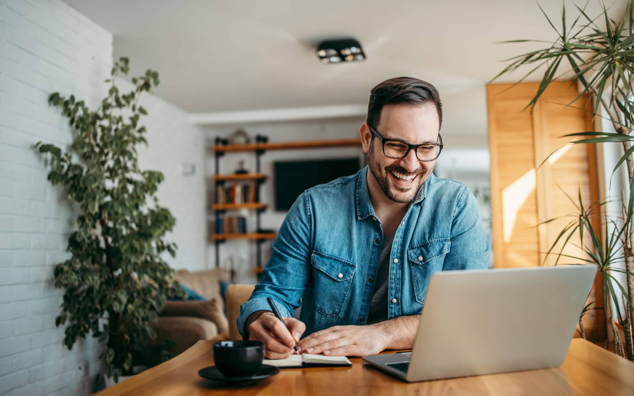 Bild: Junger Mann lächelt einen Laptop an, in dem eine Besprechung läuft.