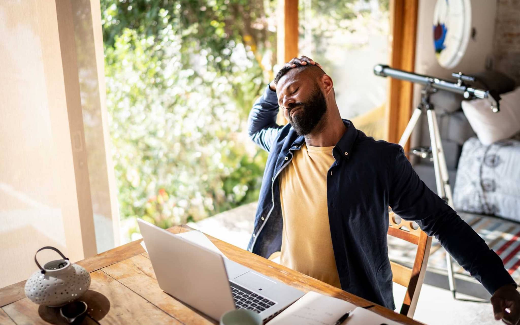 Bild: Mann neigt seinen Kopf zur Seite und hat die Hand an der Schläfe, um sich zu dehnen. Aktive Pause von der Arbeit.