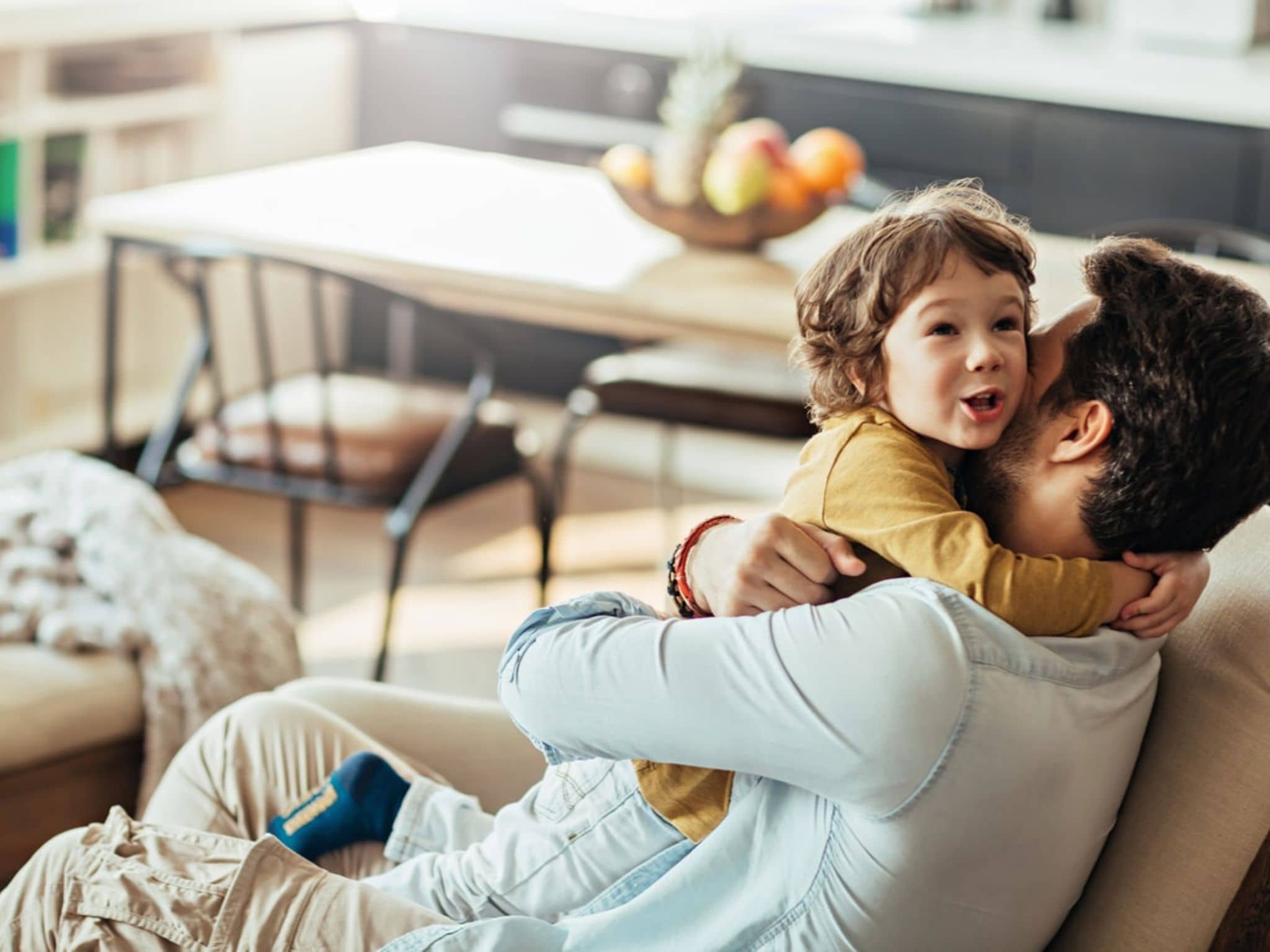 Bild: Vater umarmt sein Kind, eine fröhliche Situation im Familienalltag.