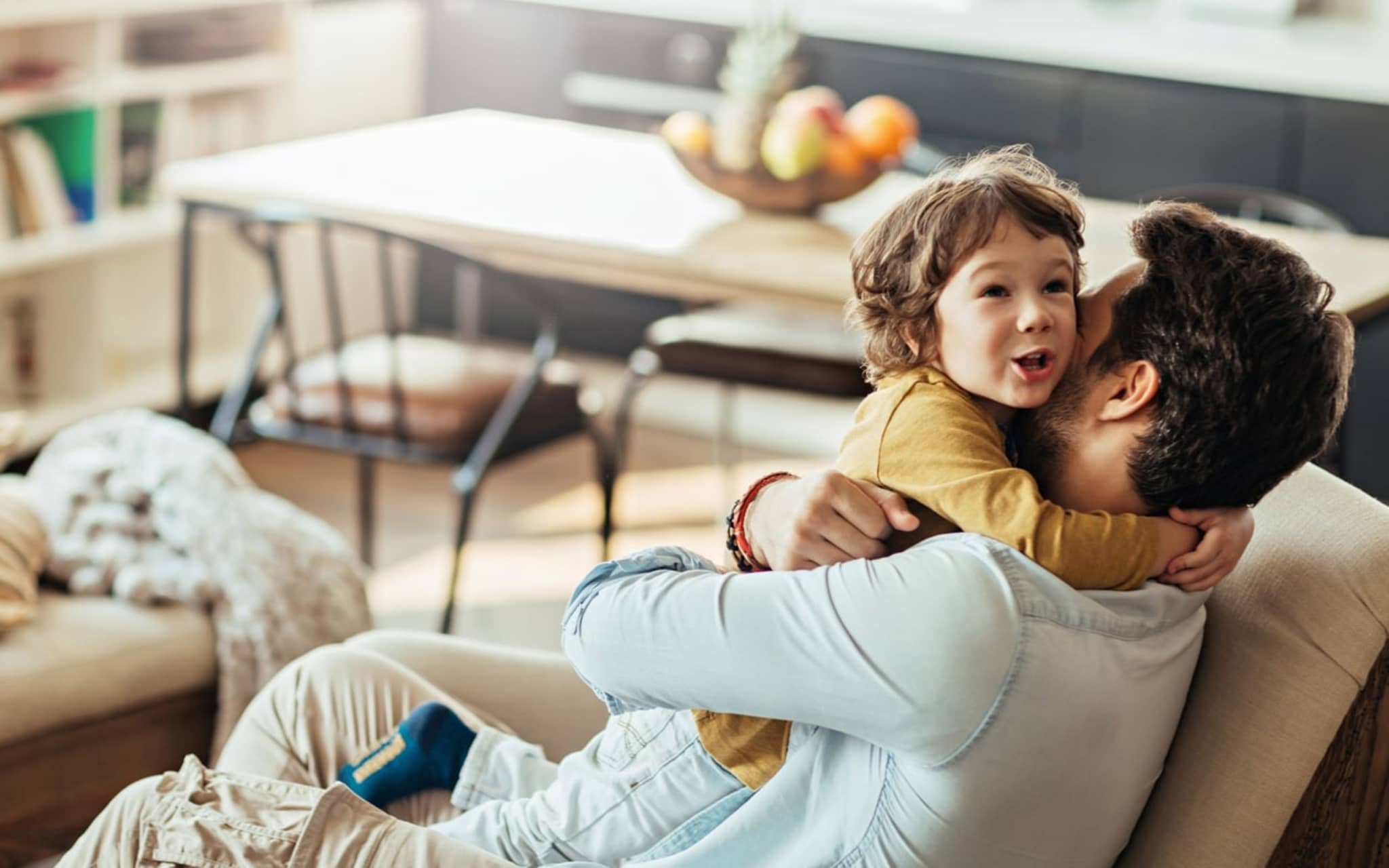Bild: Vater umarmt sein Kind, eine fröhliche Situation im Familienalltag.