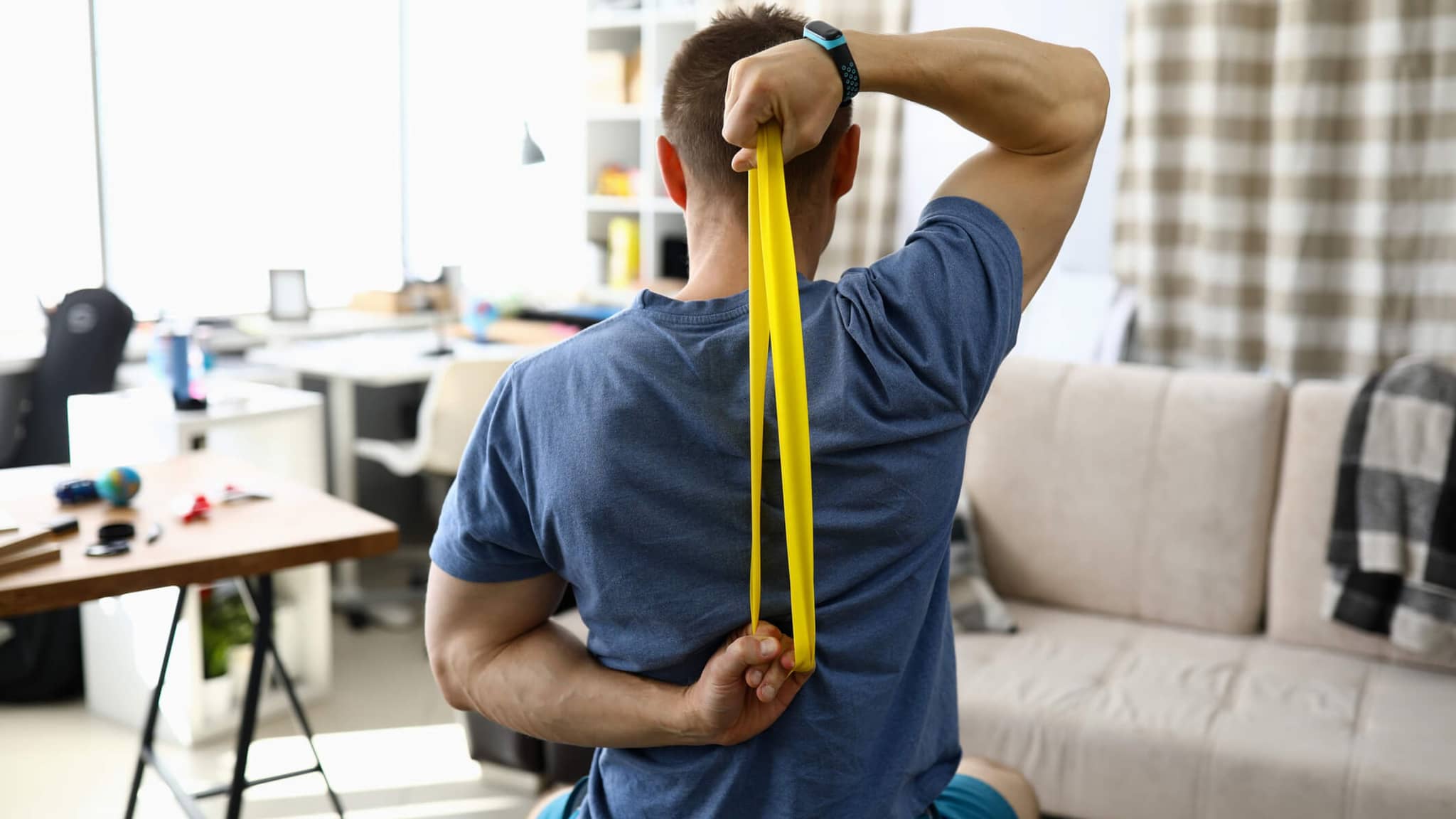 Bild: Online-Seminar Rückengesundheit: Mann benutzt gelbes Theraband hinter seinem Rücken.