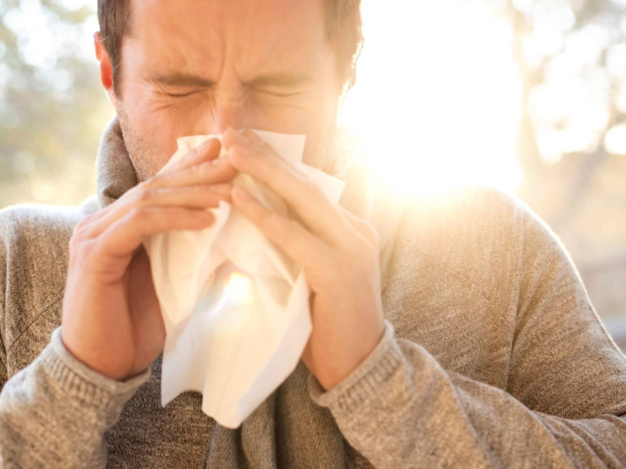 Ein Mann niest in ein Taschentuch aufgrund seiner Allergie.