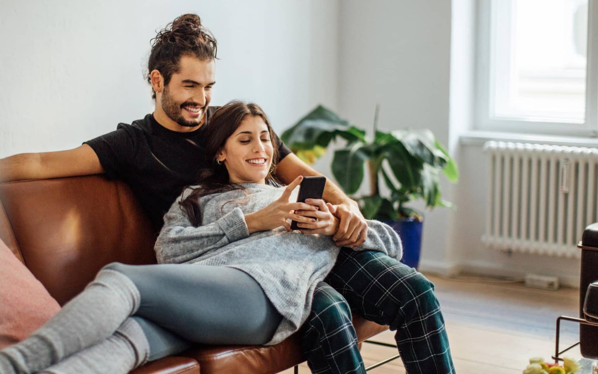 Bild: Paar auf dem Sofa informiert sich am Handy.