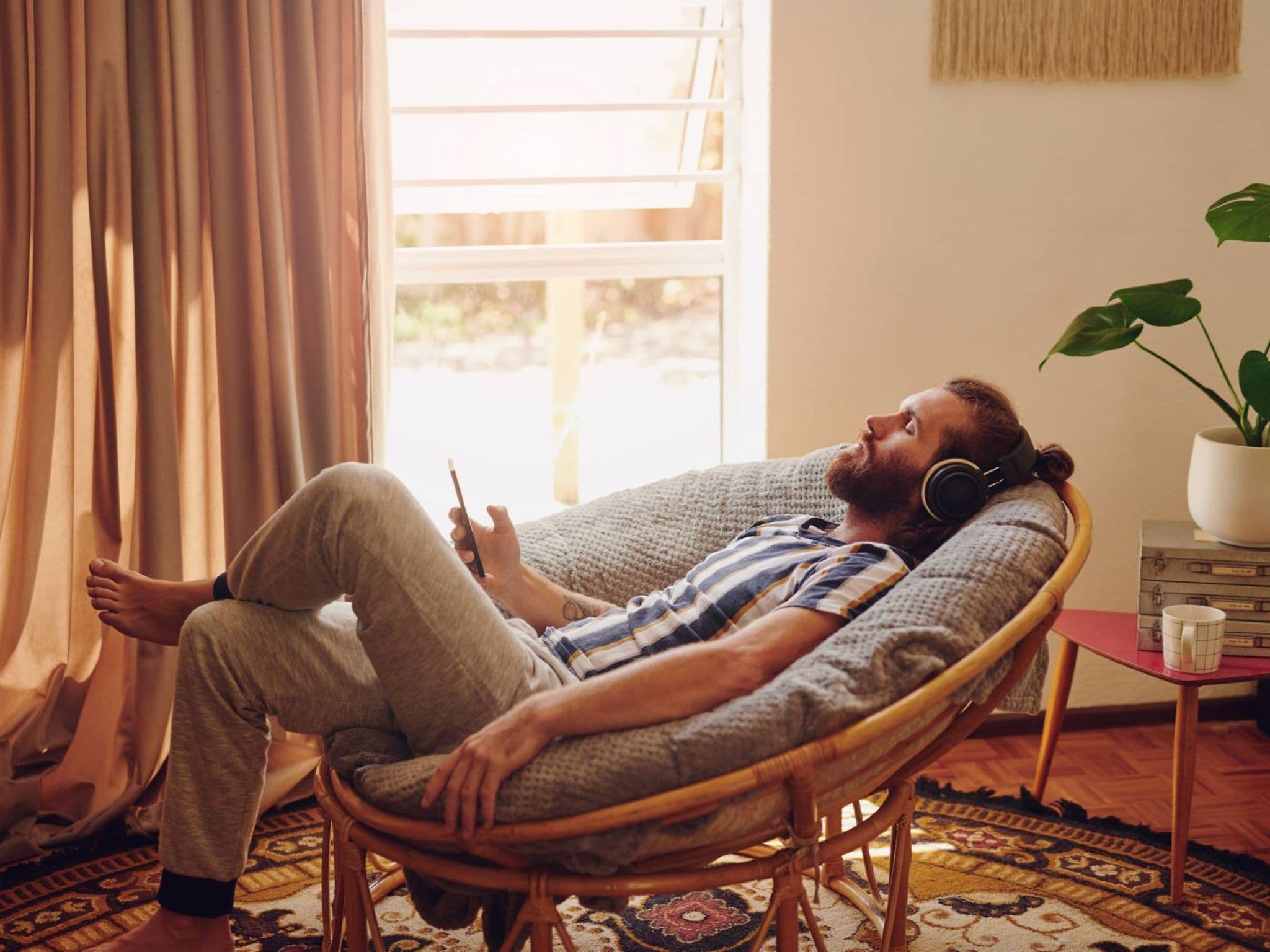 Entspannungstechniken: Mann liegt im Stuhl und hört entspannt Musik