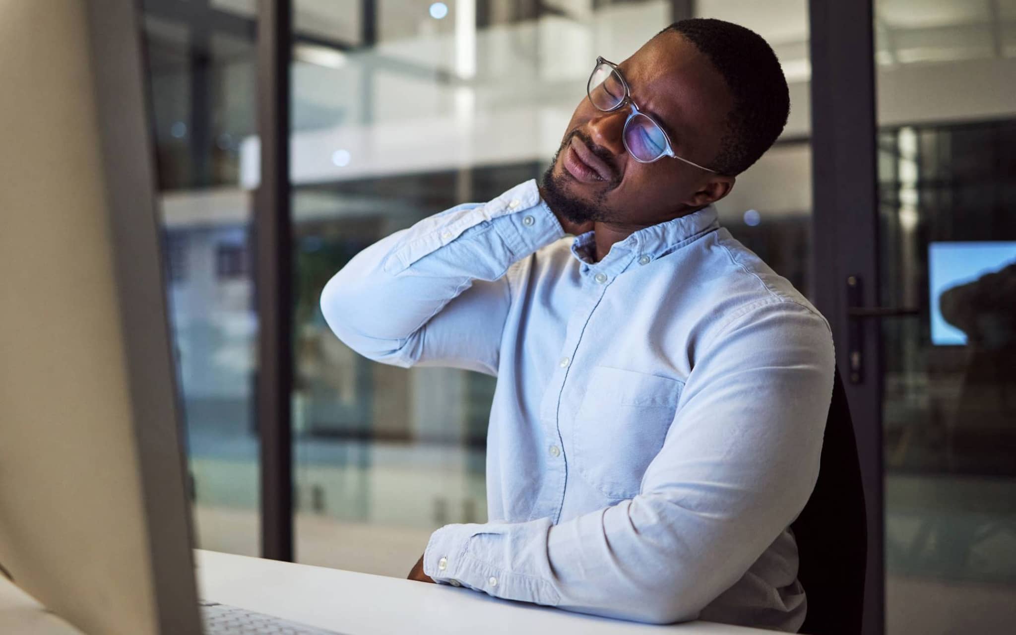 Mann hält sich mit schmerzverzerrtem Gesicht den Nacken