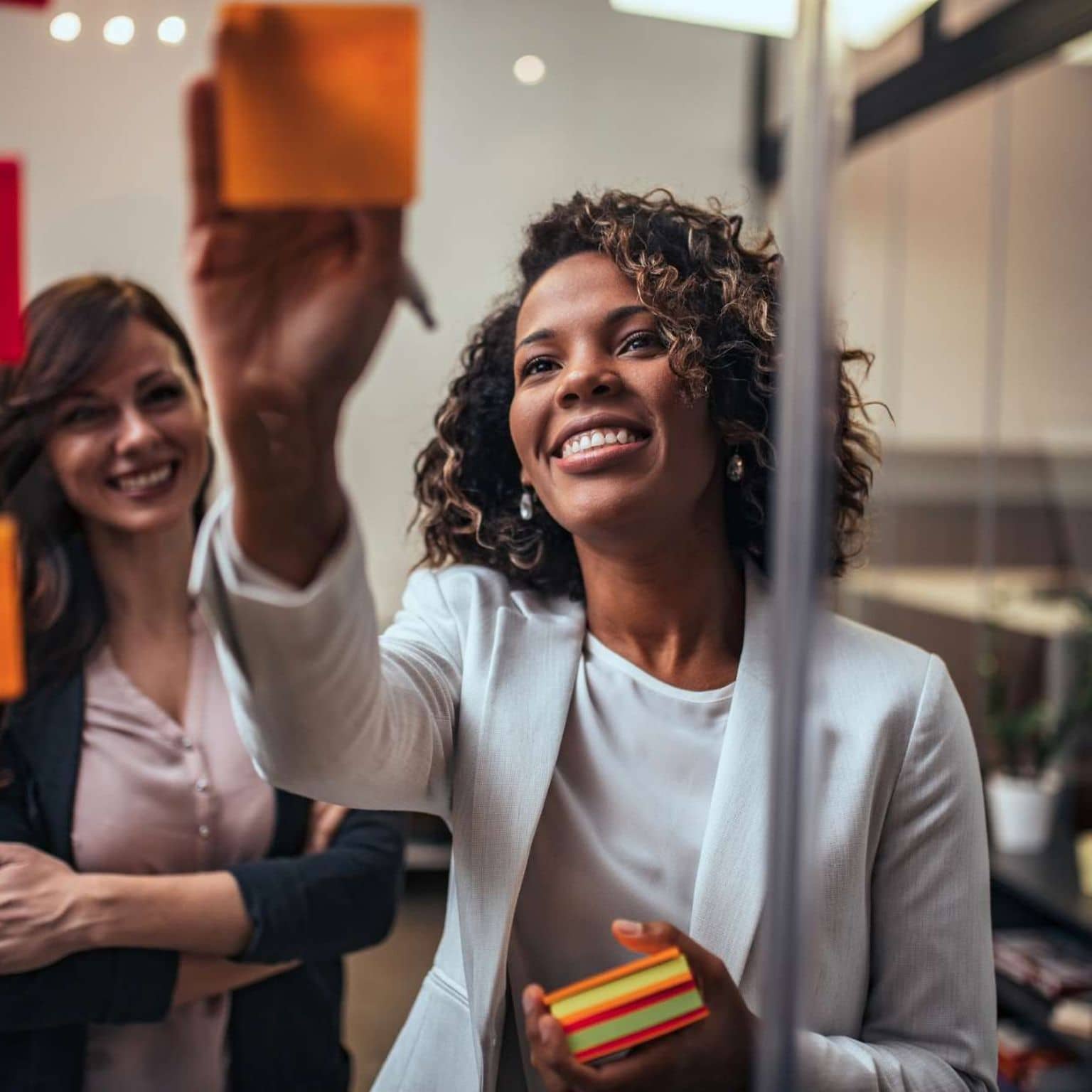 Bild: Frau klebt Post ist an eine Glaswand und lächelt.