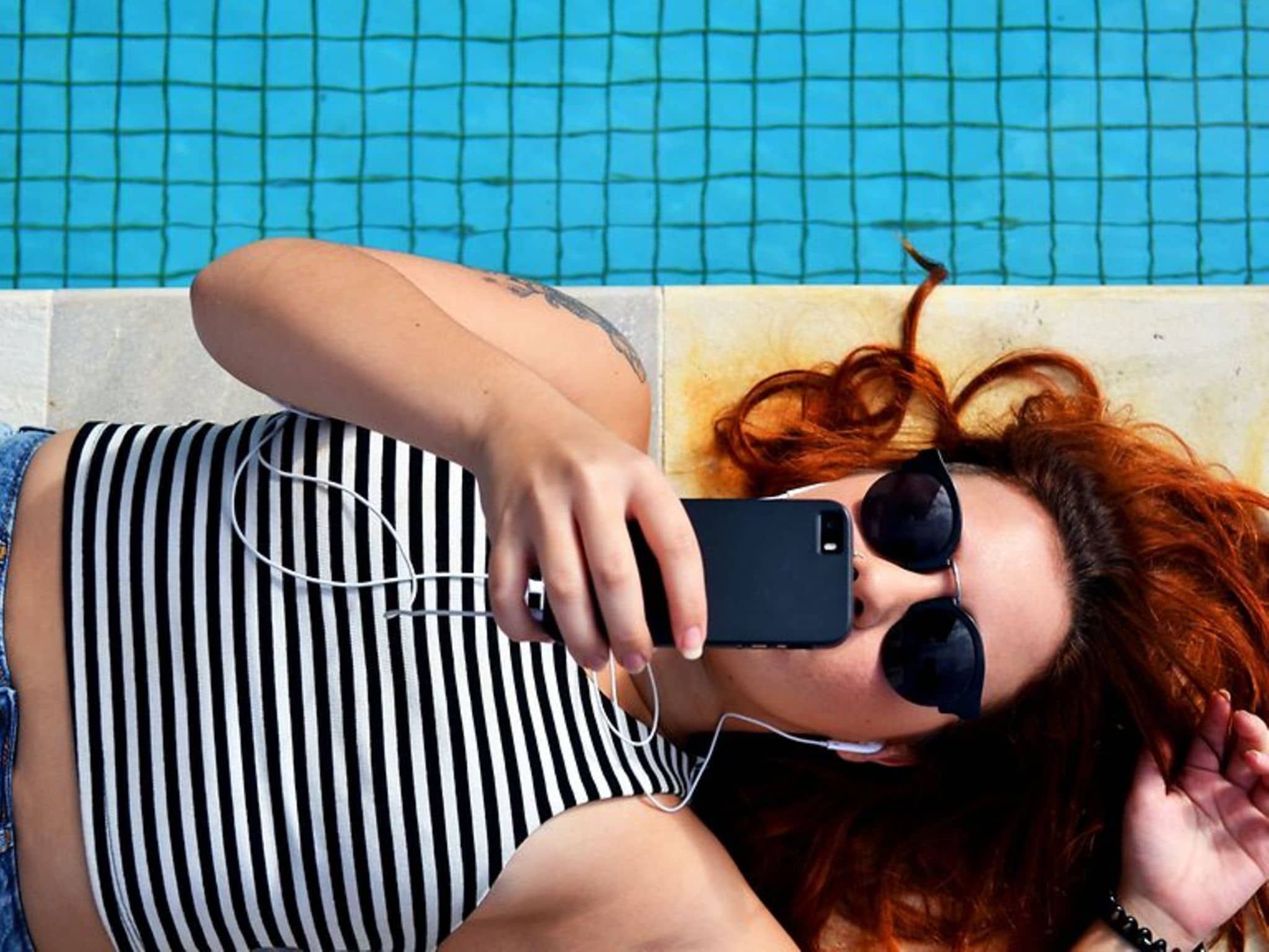 Symboldbild für Smartphone - Auswirkungen auf die Augen: Ein Teenager-Mädchen liegt auf dem Boden und starrt in ihr Smartphone