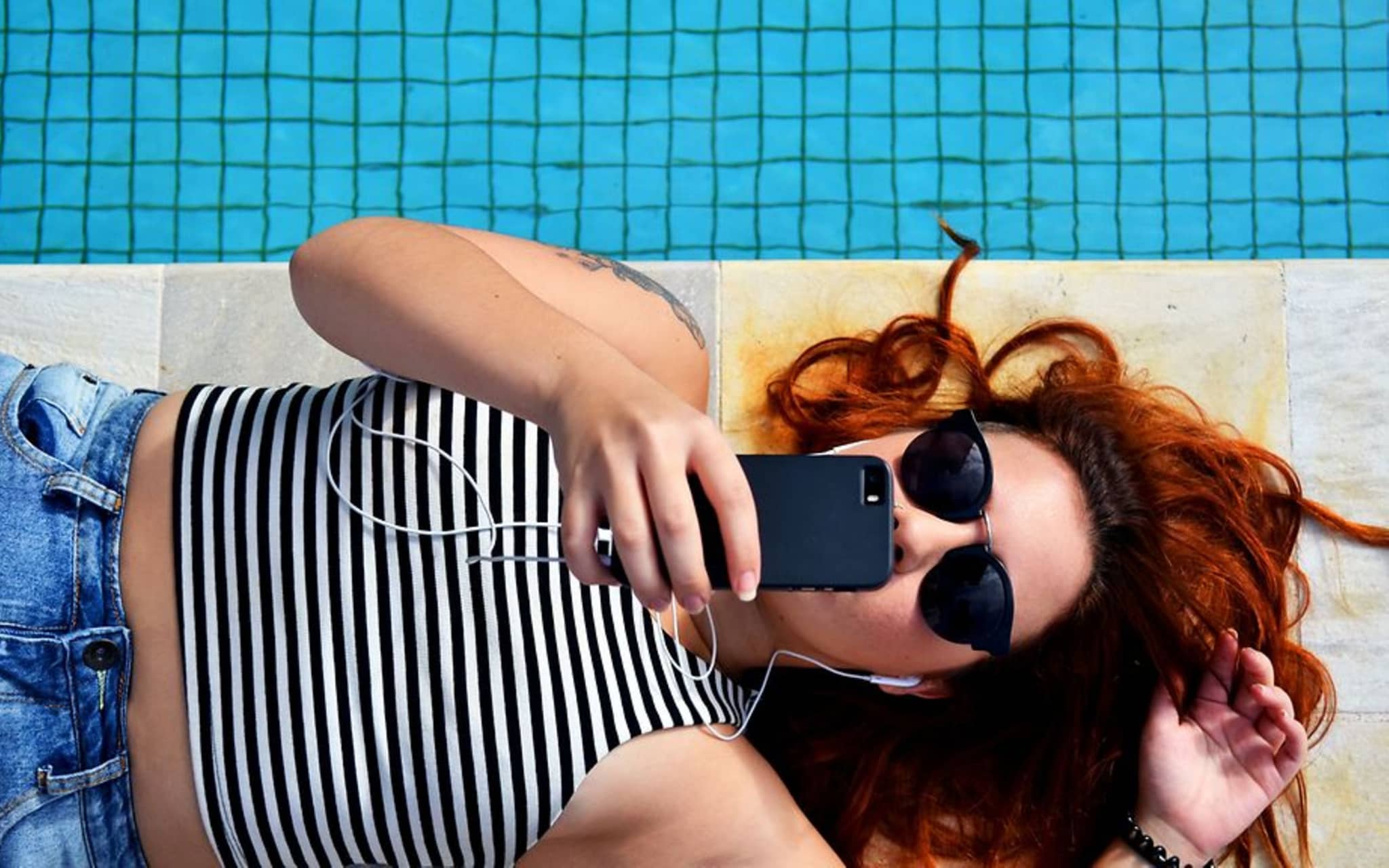 Symboldbild für Smartphone - Auswirkungen auf die Augen: Ein Teenager-Mädchen liegt auf dem Boden und starrt in ihr Smartphone