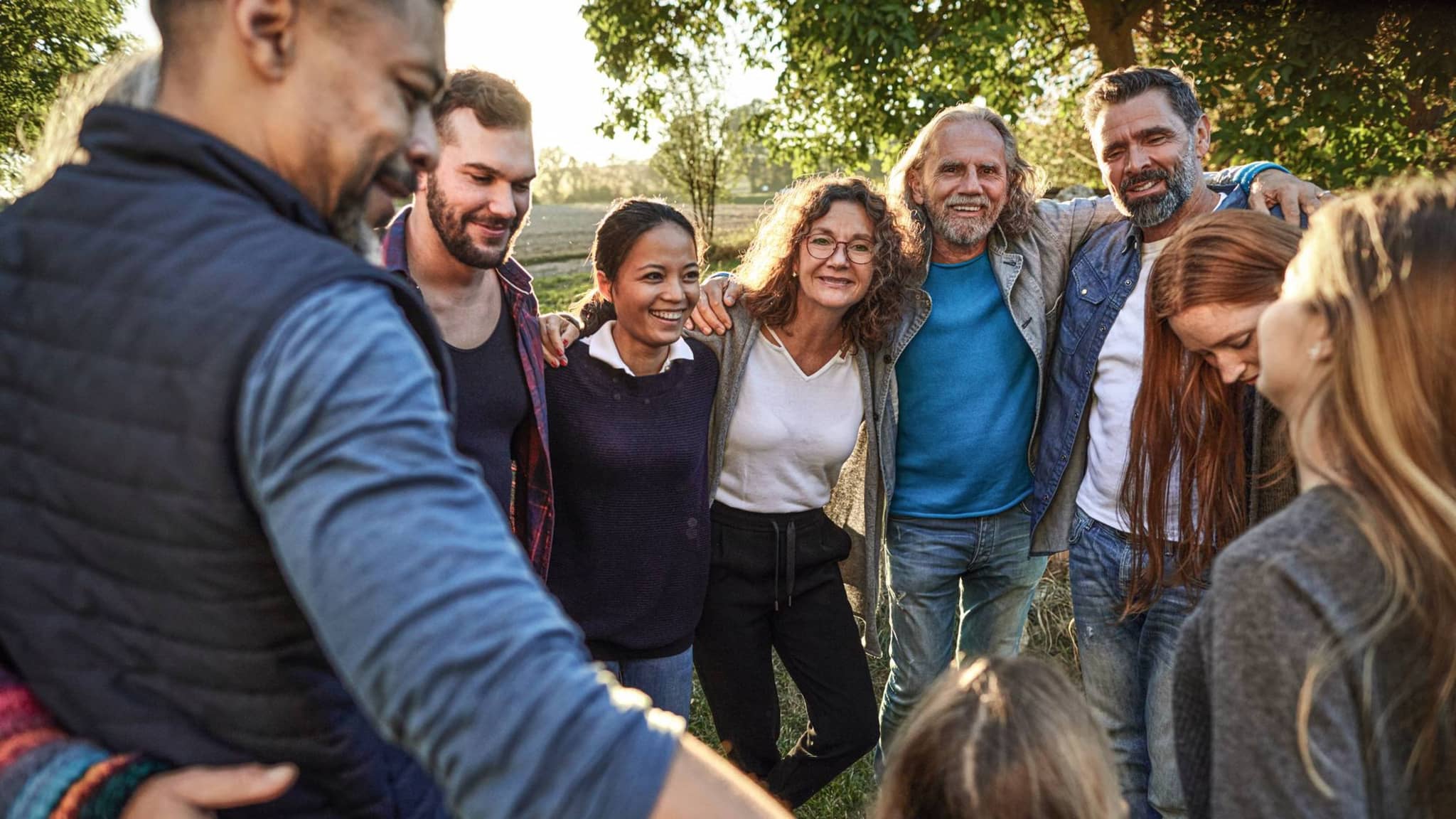 Bild: Menschen unterschiedlichen Alters umarmen sich draußen.