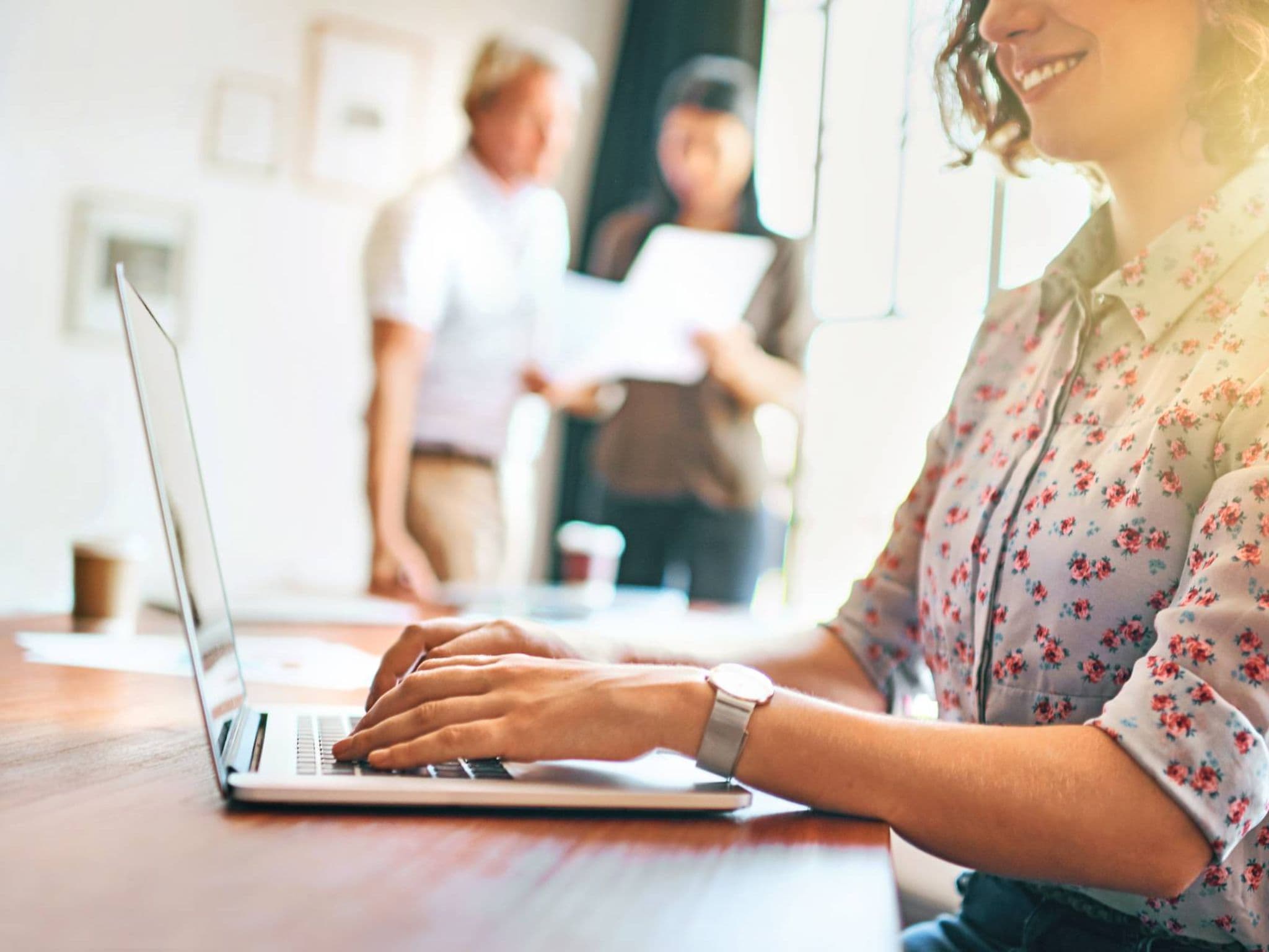 Bild: Junge Frau mit geblümter Bluse am Laptop