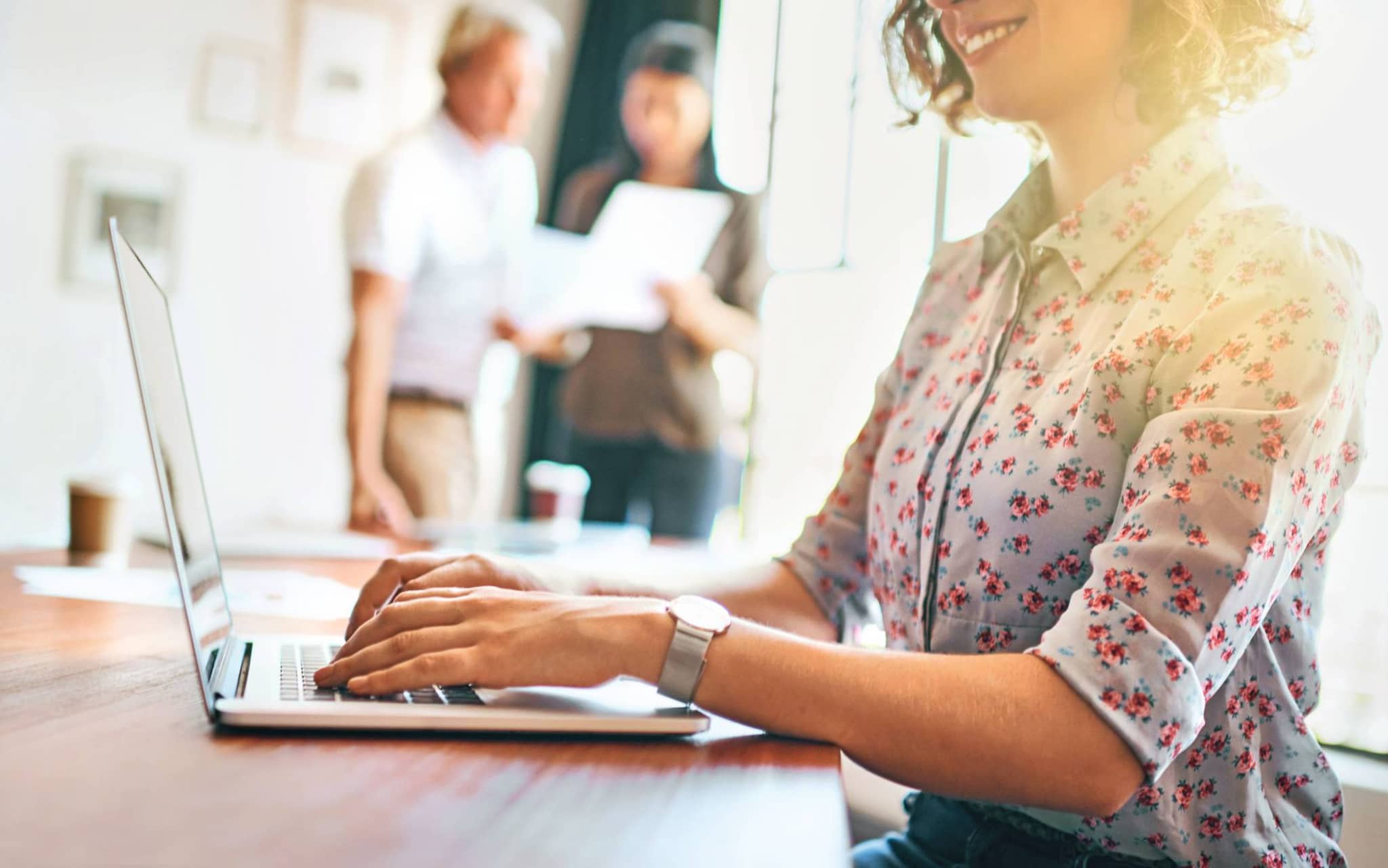 Bild: Junge Frau mit geblümter Bluse am Laptop