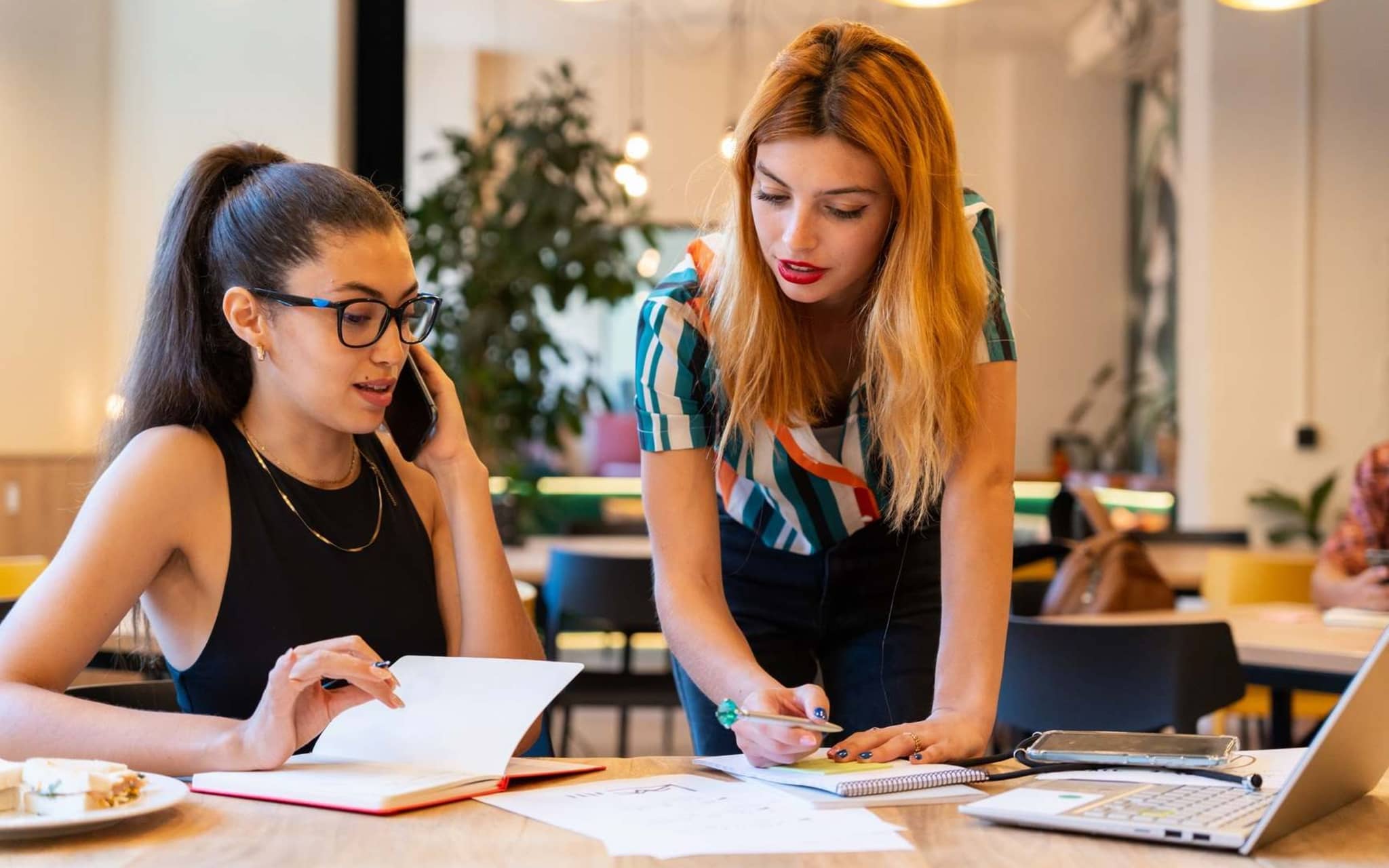 Symbolbild Beitragserstattung: Zwei Kolleginnen im Gespräch über Dokumente.