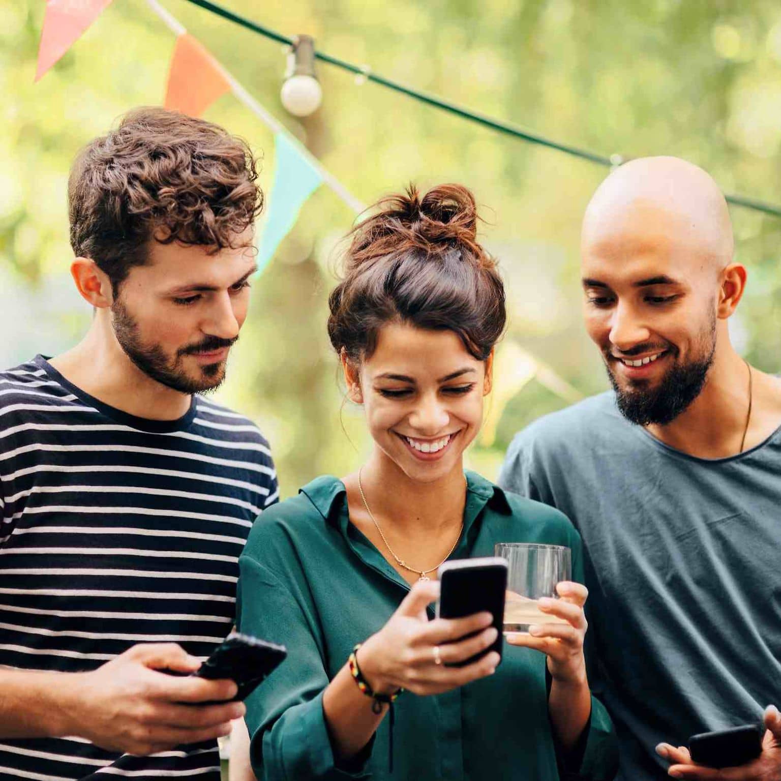 Bild: Drei Menschen checken auf dem Smartphone die neuesten Infos