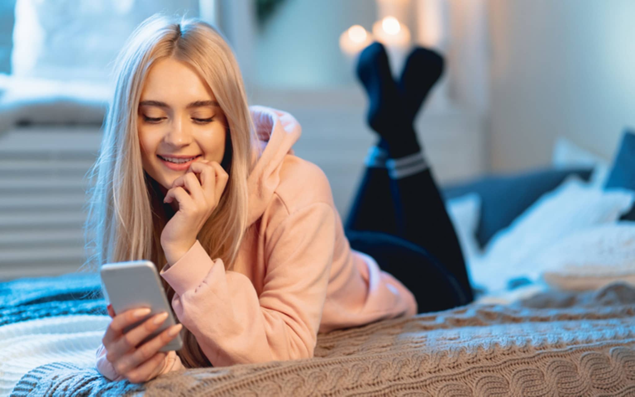Symbolbild Anatomie der Frau: Ein junges Mädchen liegt auf dem Bett und liest am Smartphone