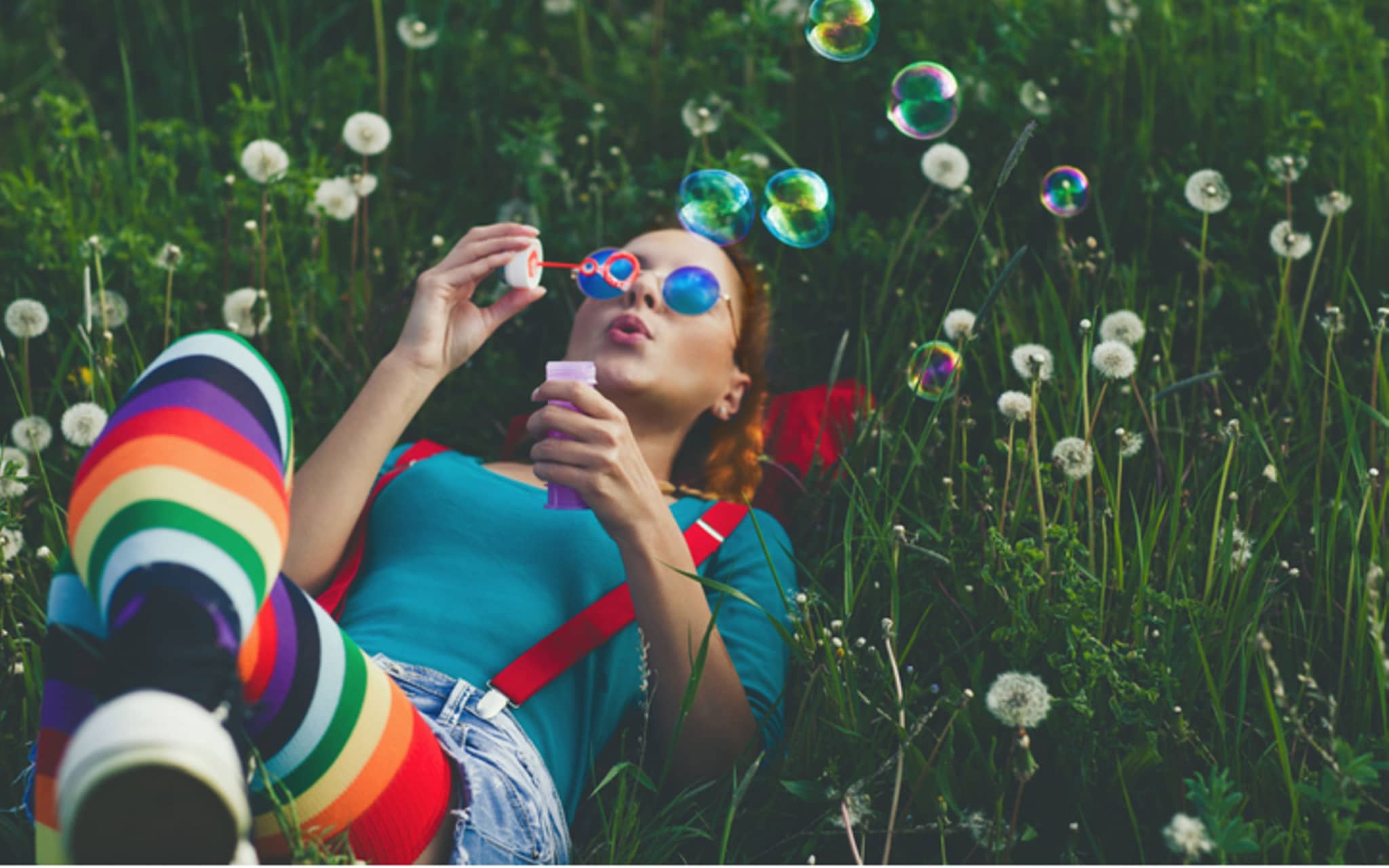 Symbolbild für Jungfernhäutchen: Ein Teenagermädchen liegt auf einer Wiese und macht Seifenblasen