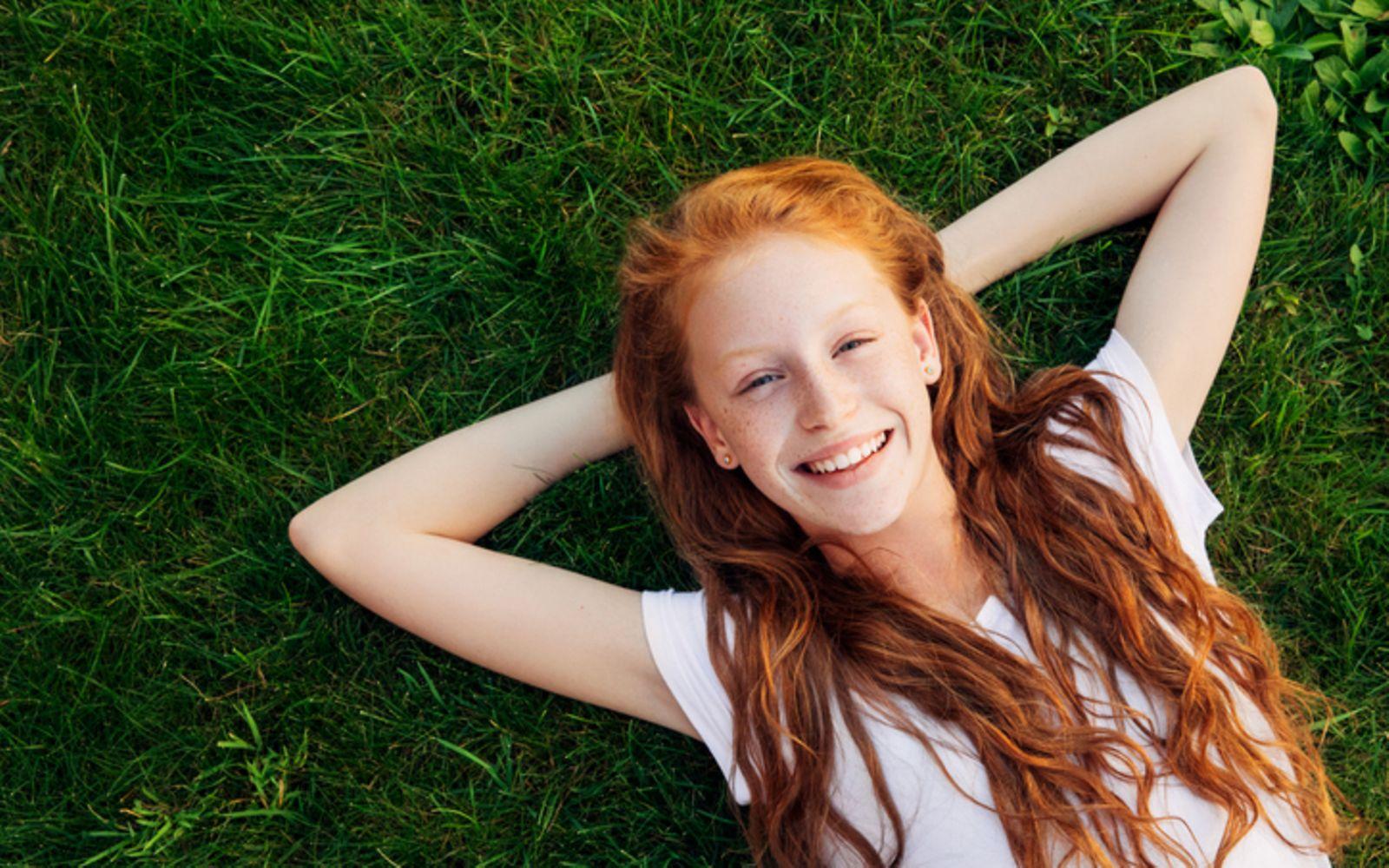 Symbolbild Busen-Wissen: Ein junges Mädchen liegt auf dem Rasen