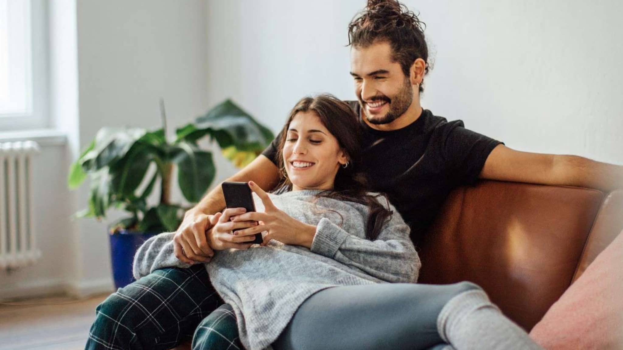 Auszeichnungen für DAK: Junges Paar sitzt auf dem Sofa und schaut gemeinsam auf ein Handy.