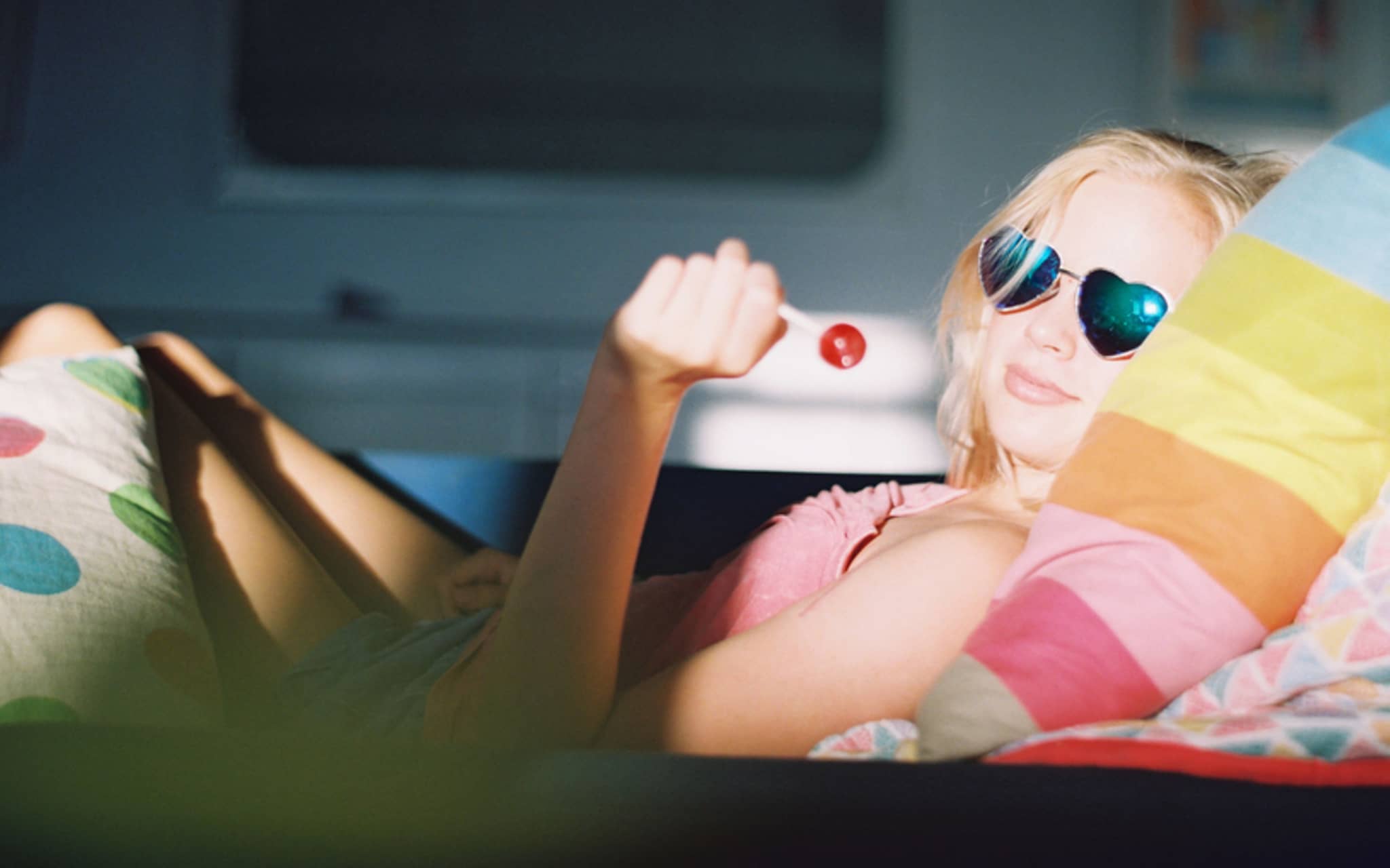 Eine Jugendliche liegt mit Lolly im Bett und hat PMS-Symptome.