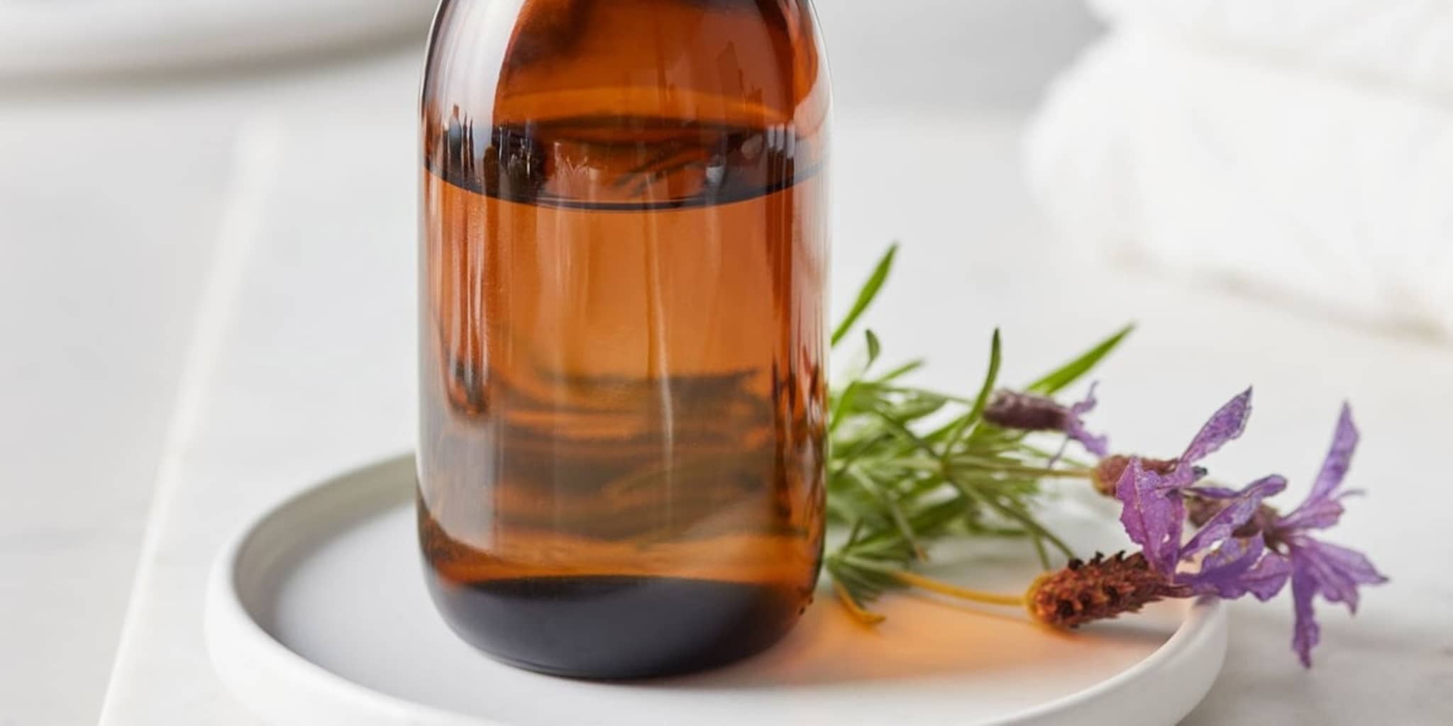 Homöopathie: Fläschchen mit homöopathischer Flüssigkeit steht neben einer Blume auf einem Tablett