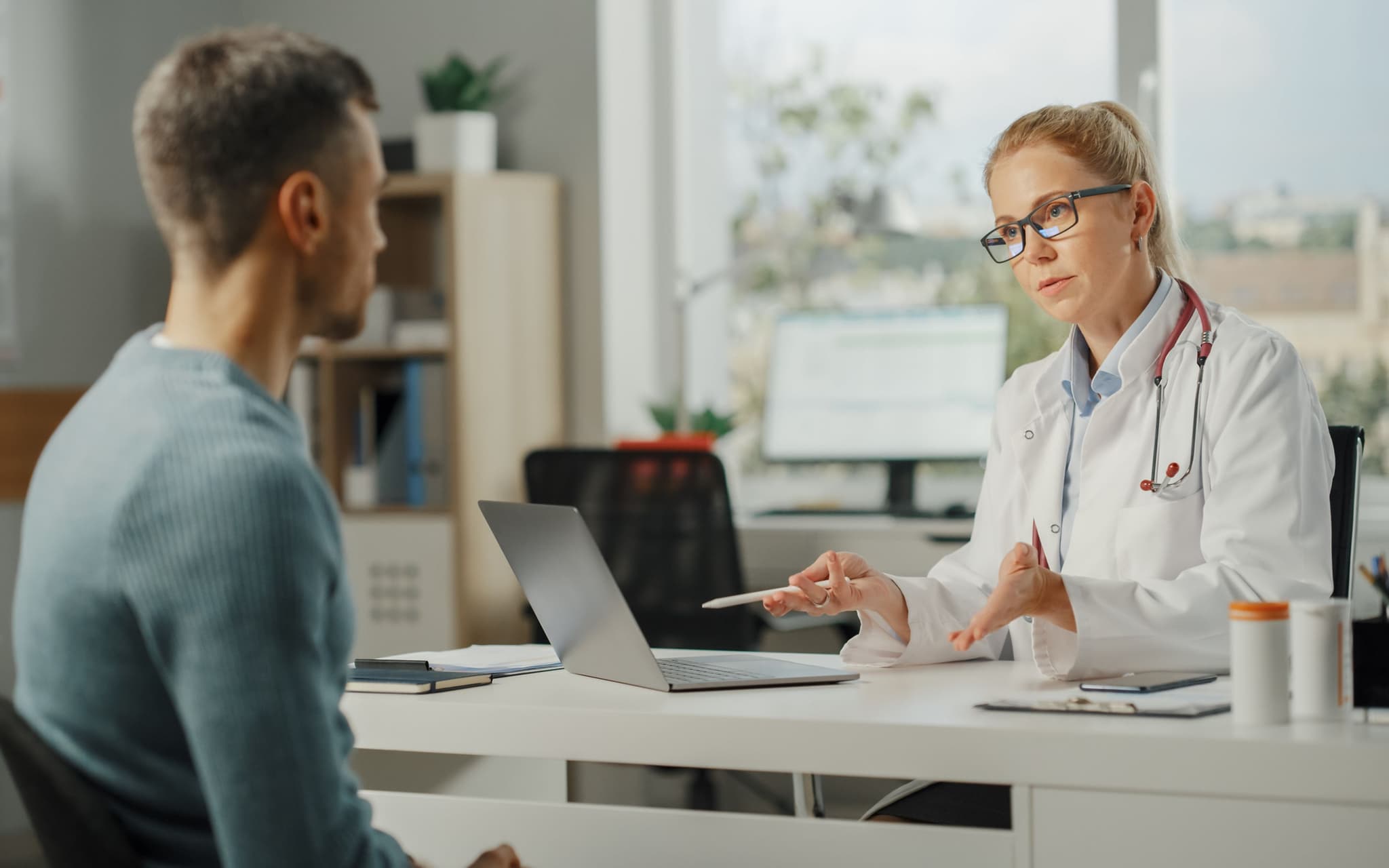 Was macht ein Urologe: Ein junger Mann sitzt im Behandlungszimmer einer Urologin und spricht mit ihr