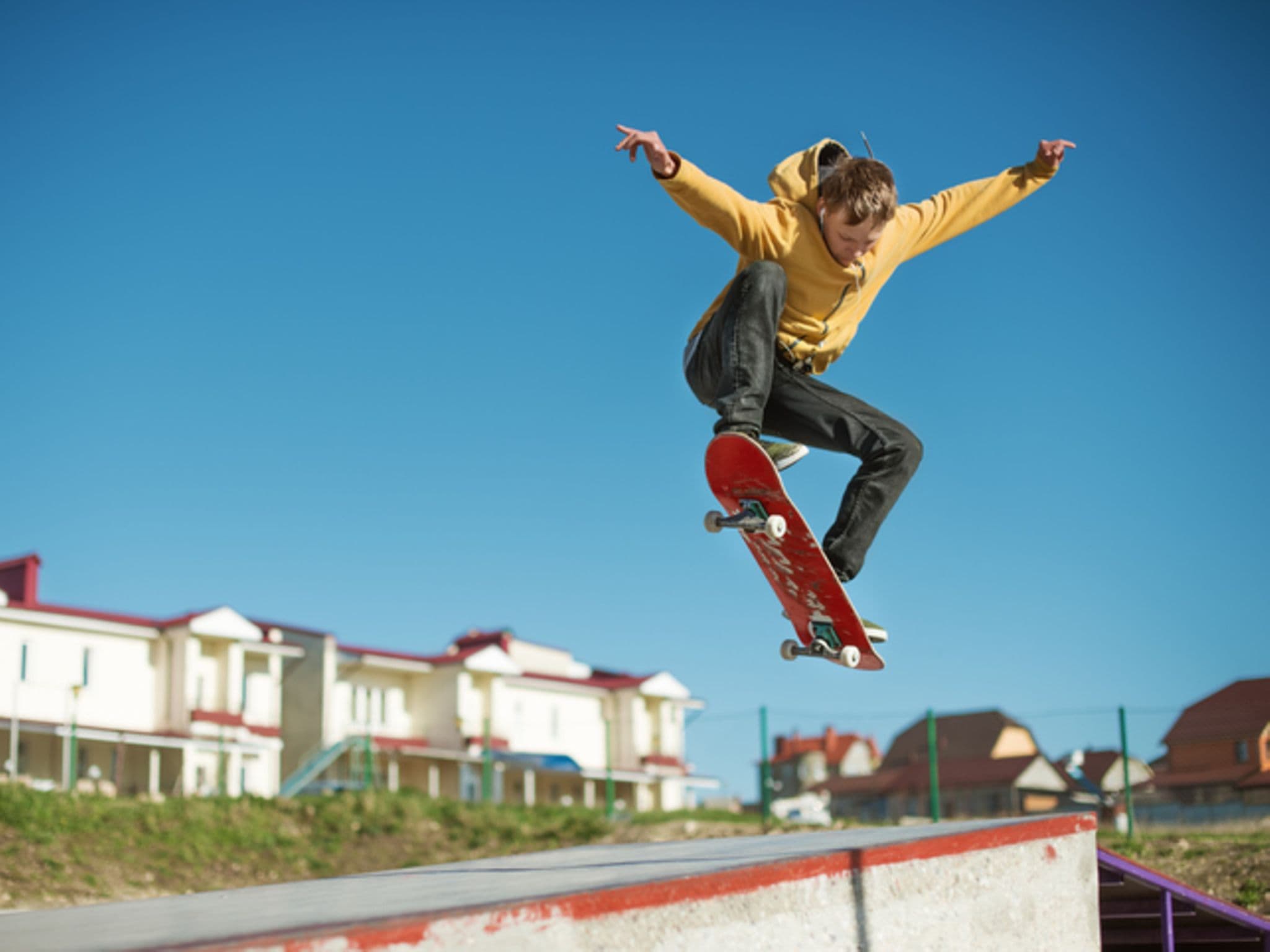 Ein Jugendlicher befindet sich mit seinem Skateboard im Höhenflug.