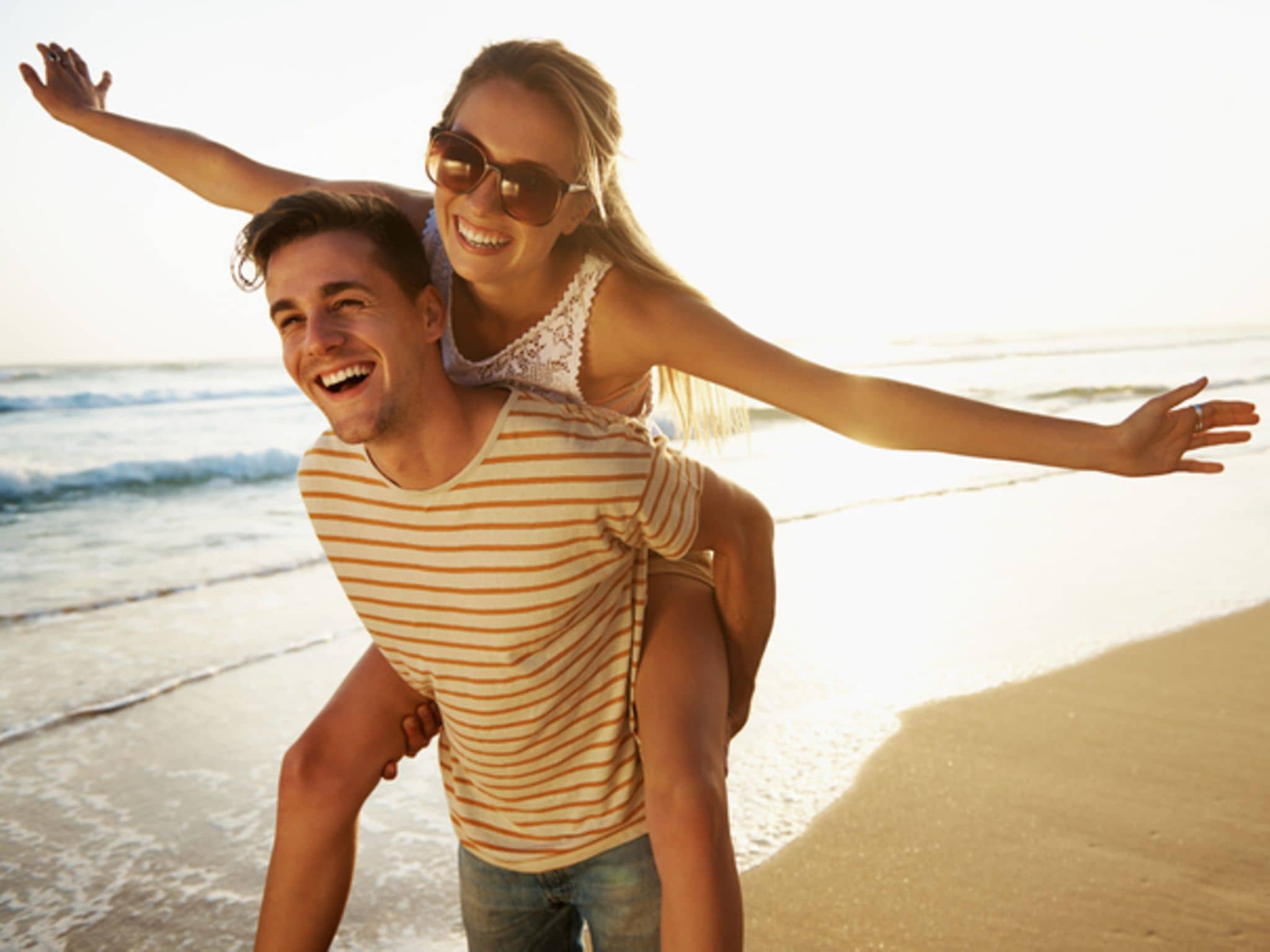 Ein junges Paar ist verliebt am Strand und fühlt sich frei.