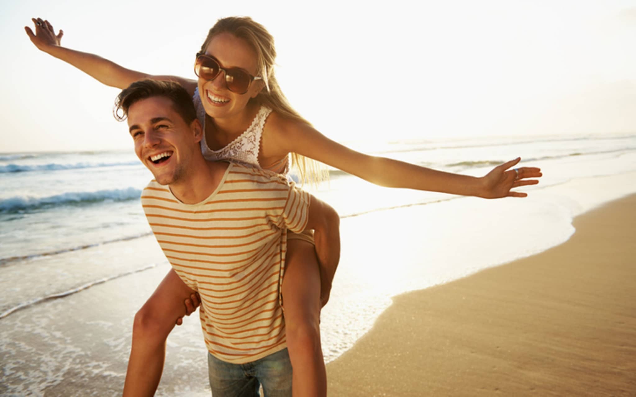 Ein junges Paar ist verliebt am Strand und fühlt sich frei.