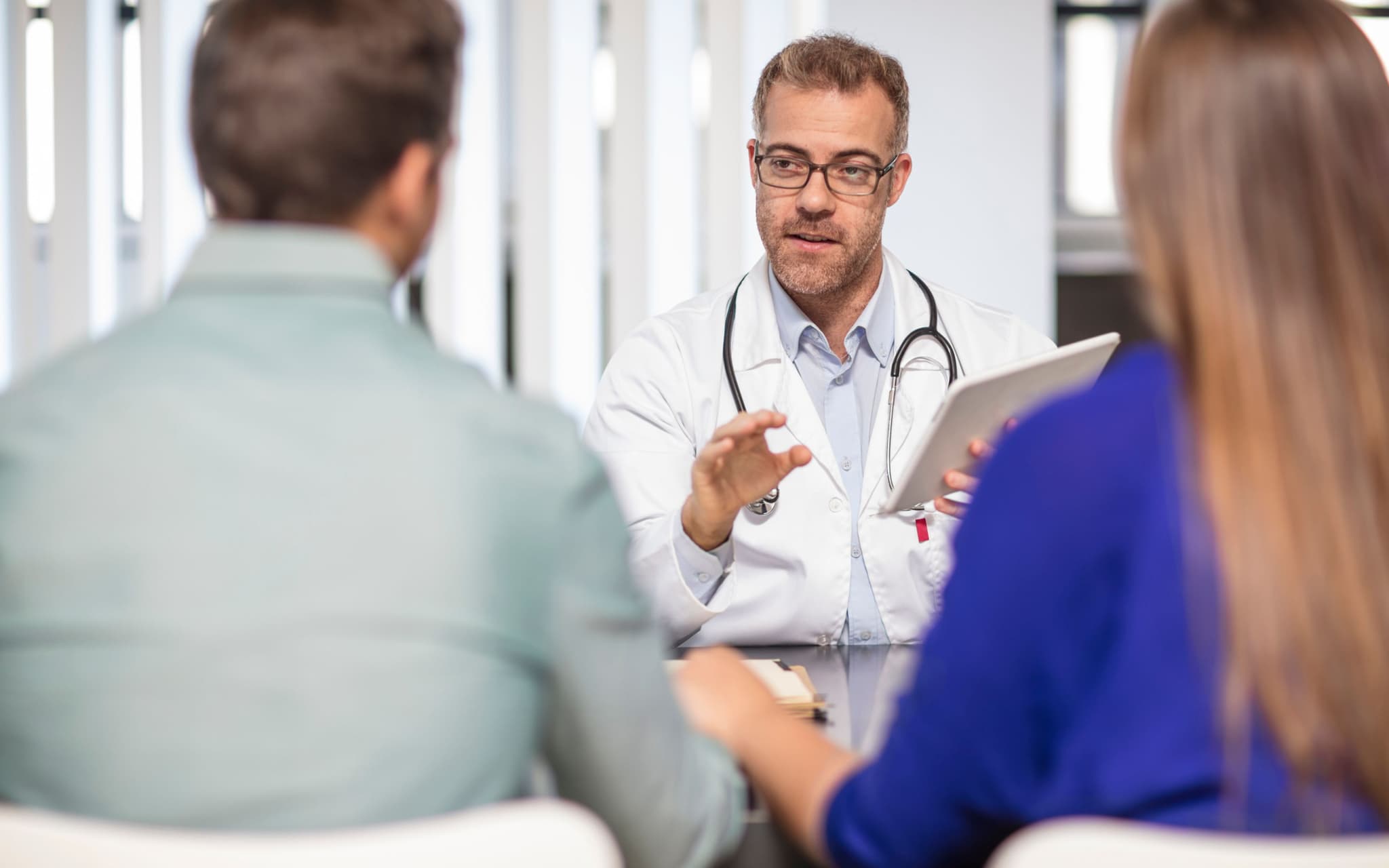 Verhütung für den Mann: Ein Paar sitzt in einer Arztpraxis und führt ein Gespräch mit einem Arzt