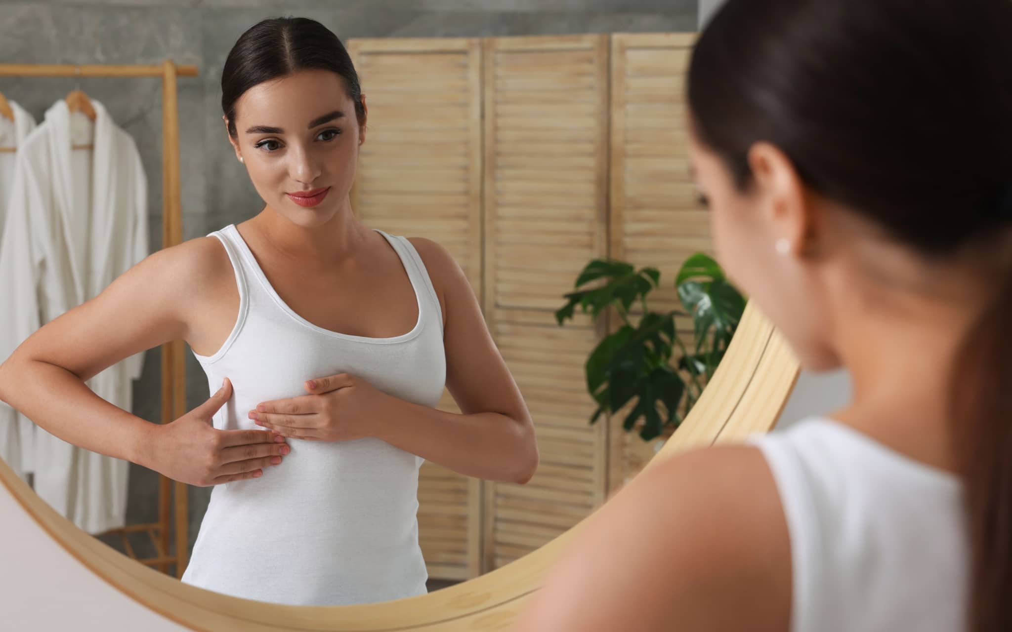 Brust abtasten: Eine Frau steht vor dem Spiegel und tastet ihre Brust ab