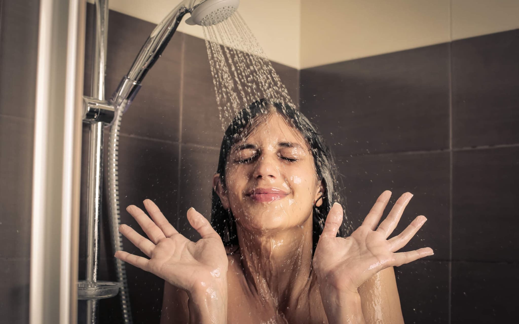 Junges Mädchen das gut gelaunt unter der Dusche steht