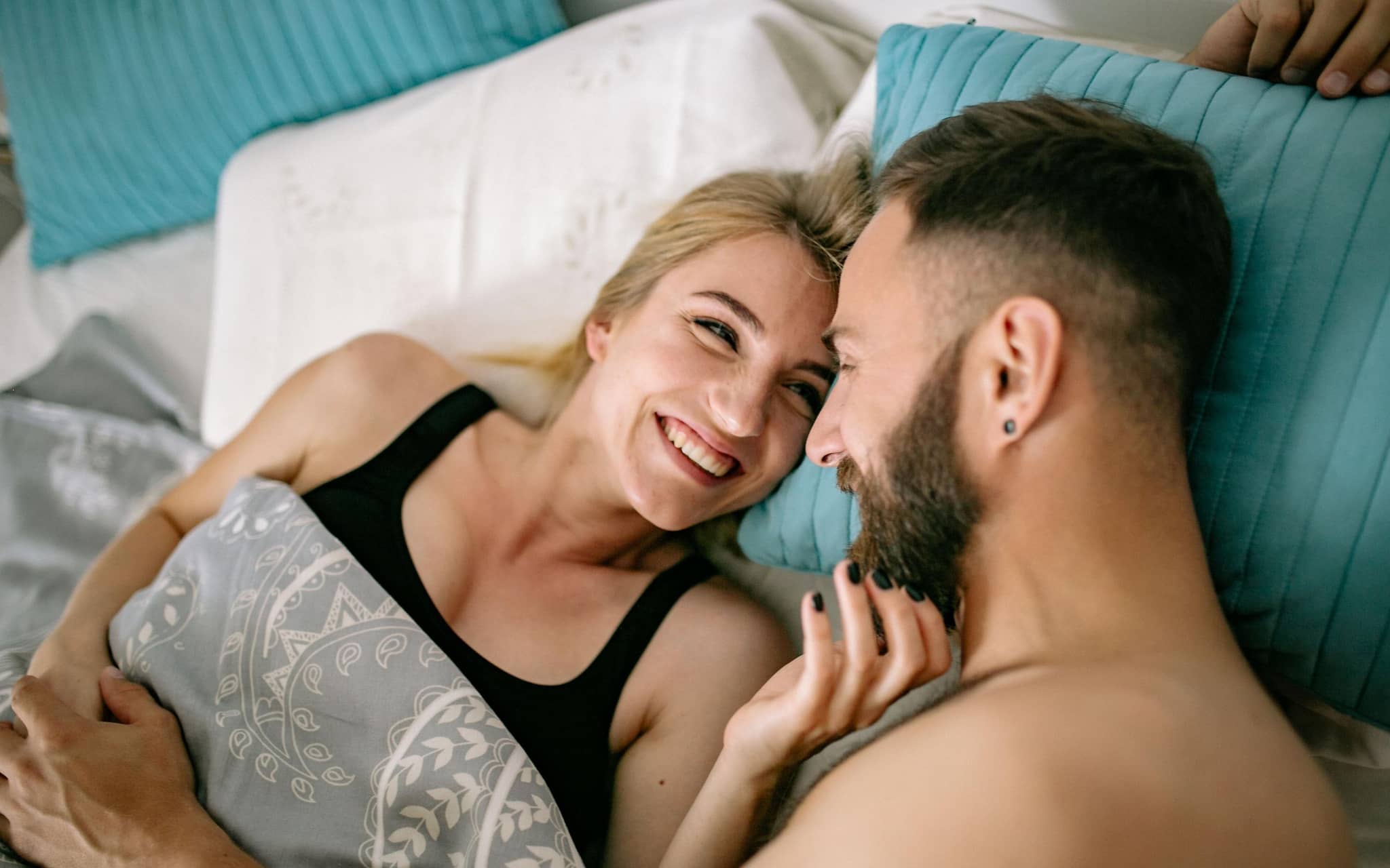 Junges Paar liegt im Bett und liebkost sich.