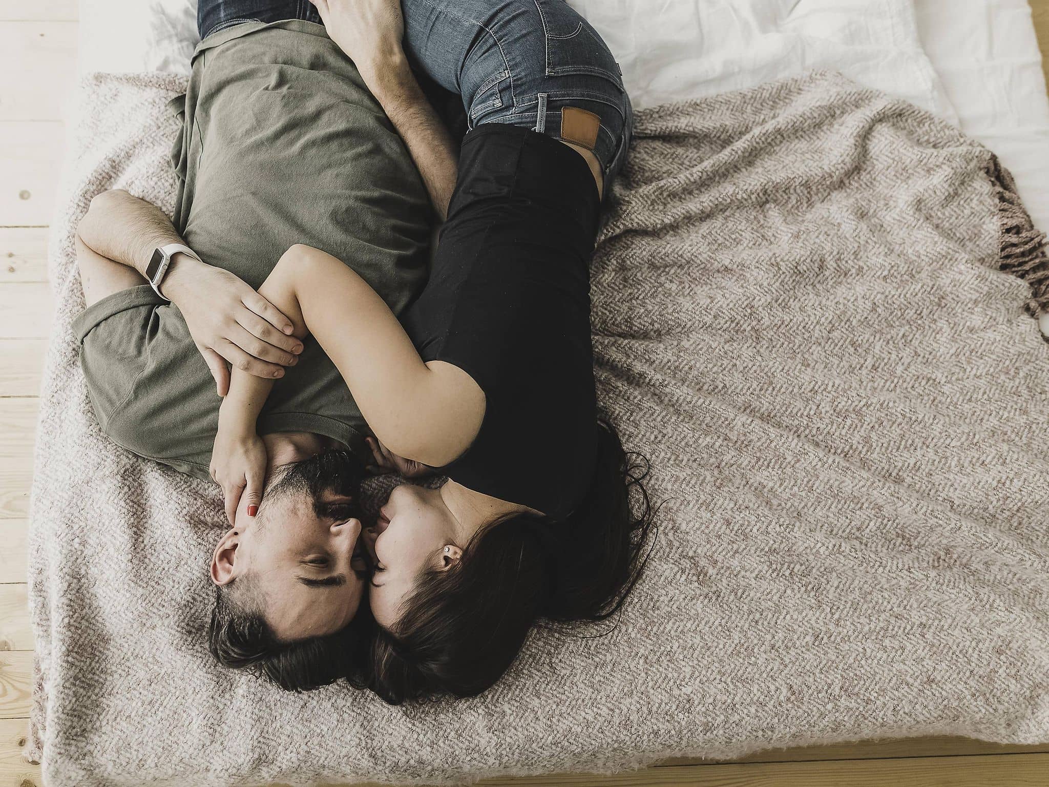 Mann und Frau liegen liebkosend im Bett.