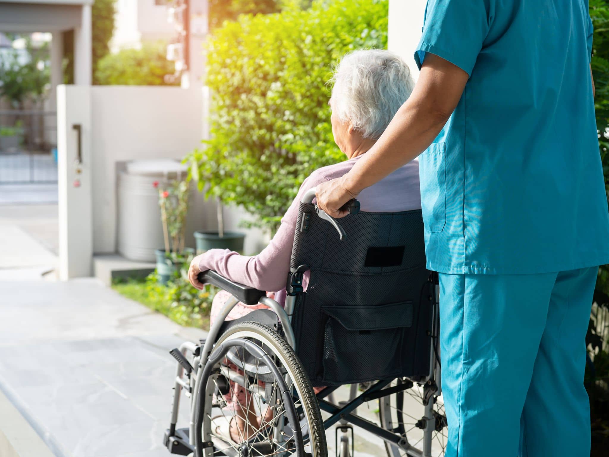 Hilfsmittel: Eine Seniorin sitzt im Rollstuhl und wird geschoben