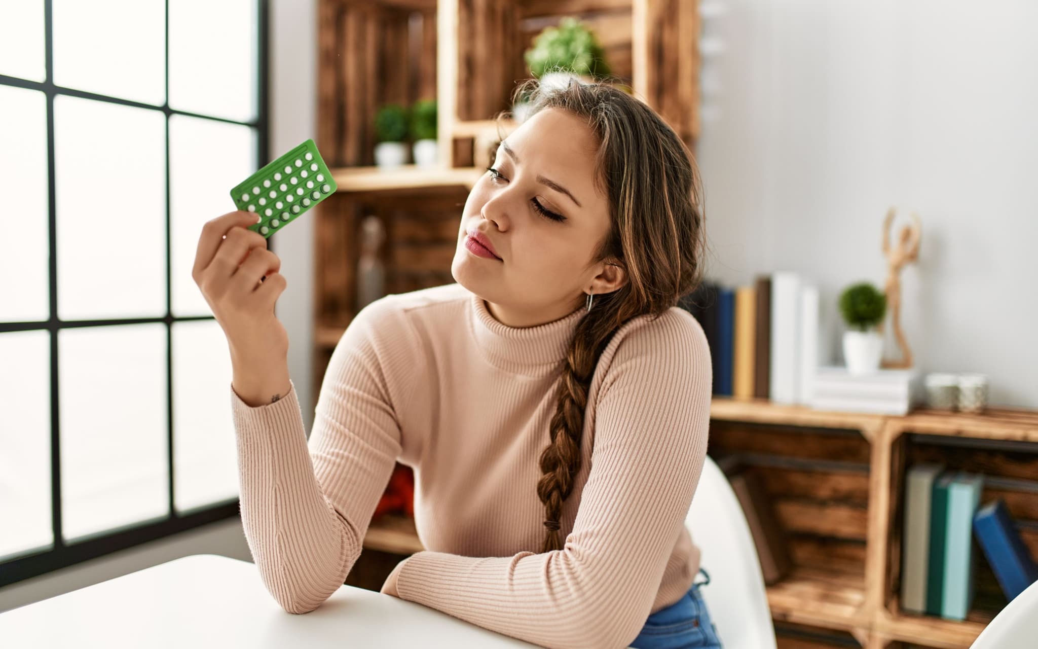 Pille absetzen: Eine Frau hält die Antibabypille in der Hand und denkt nach