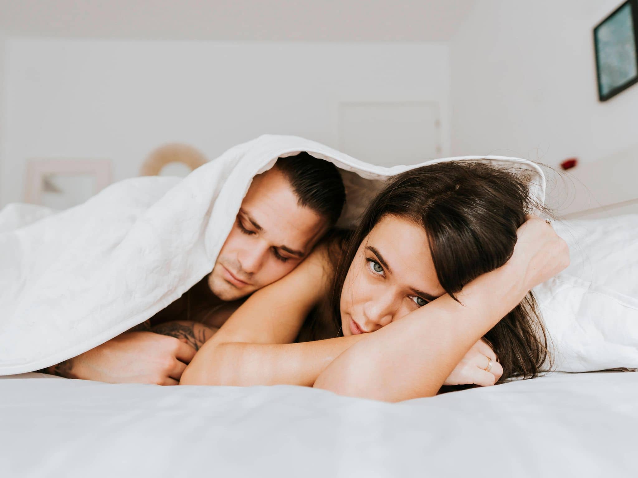 Lost Penis Syndrom: Frau und Mann unter einer Decke, Frau guckt traurig.