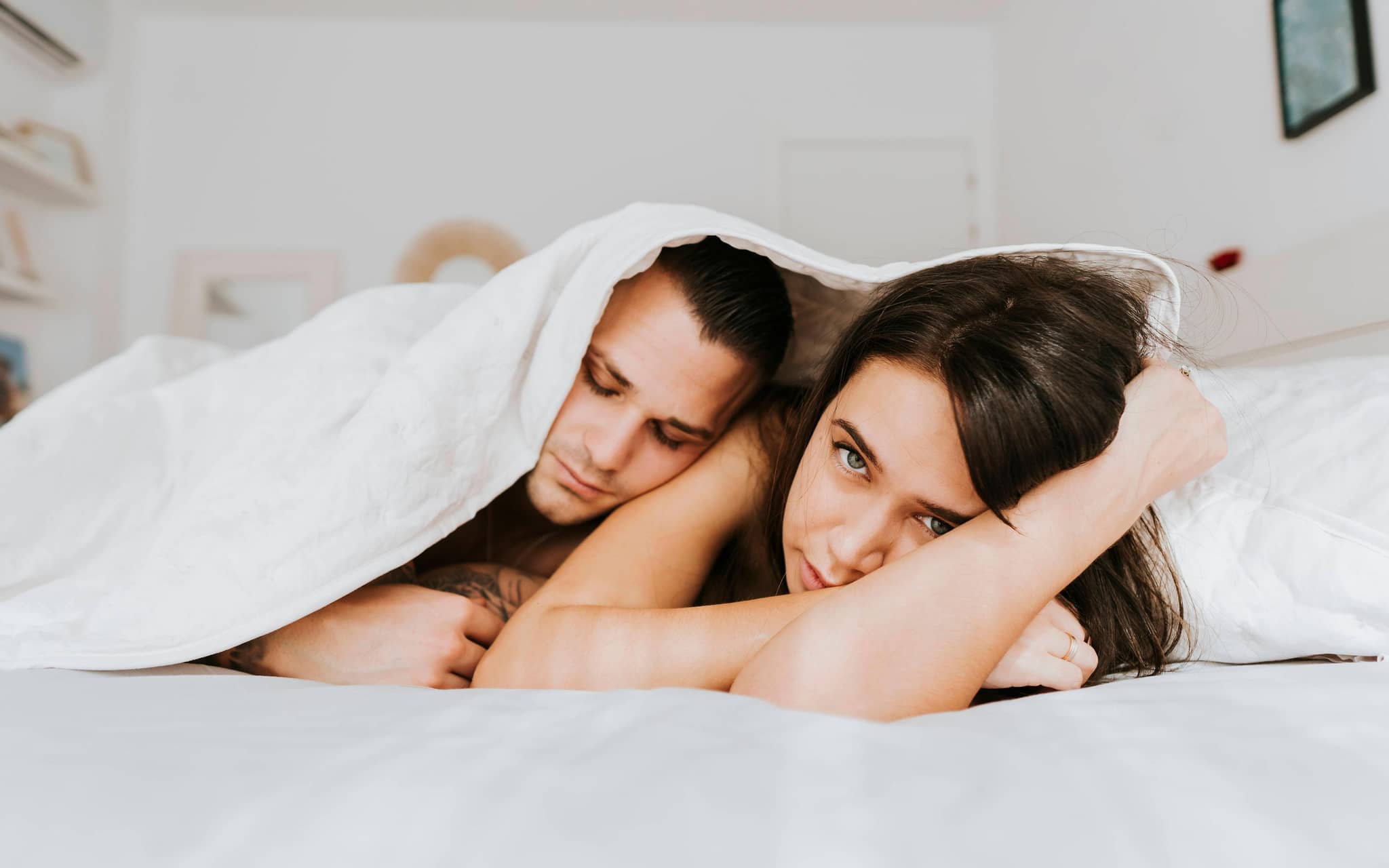 Lost Penis Syndrom: Frau und Mann unter einer Decke, Frau guckt traurig.