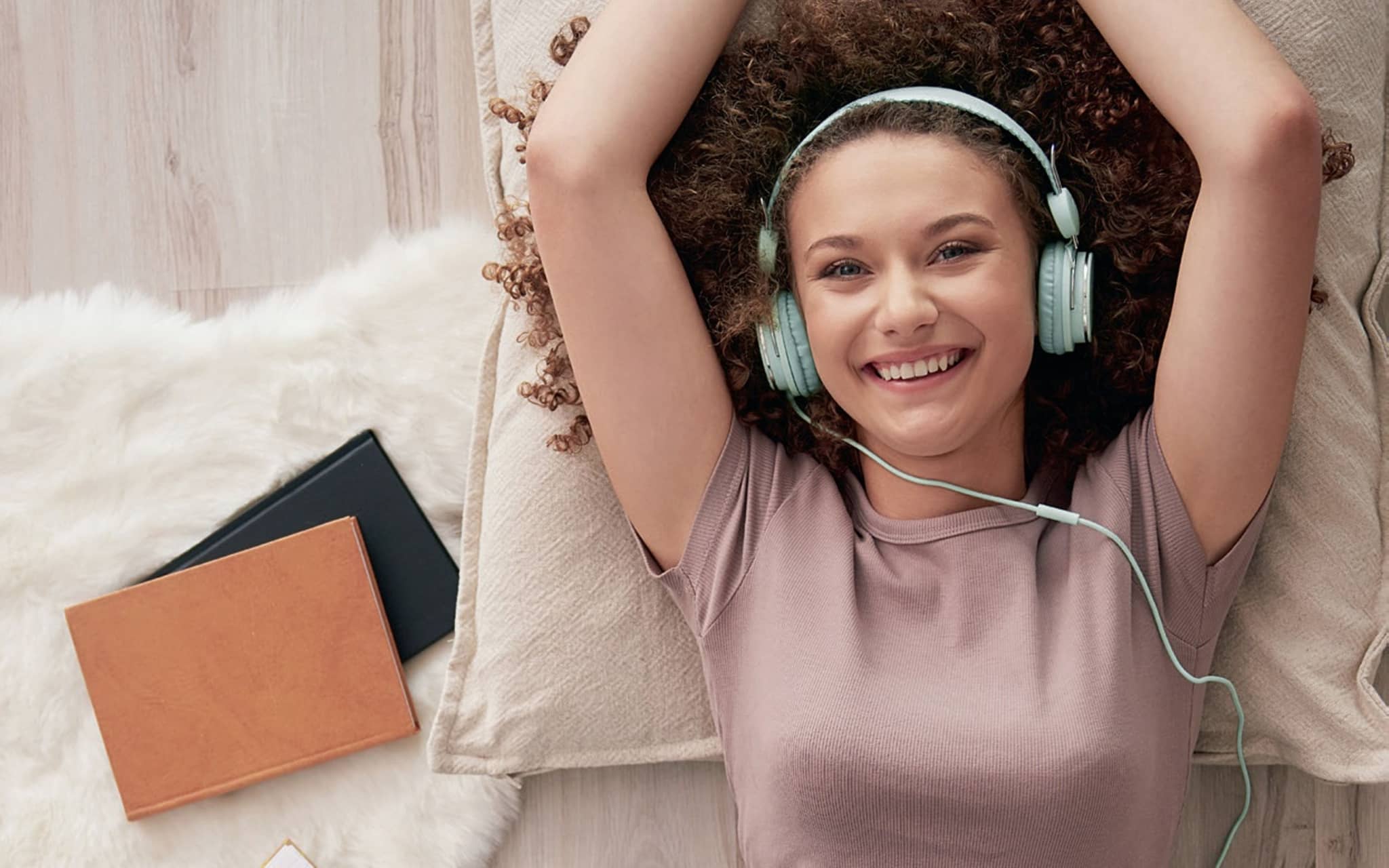 Bild: Junge Frau mit Kopfhörern liegt auf dem Boden.
