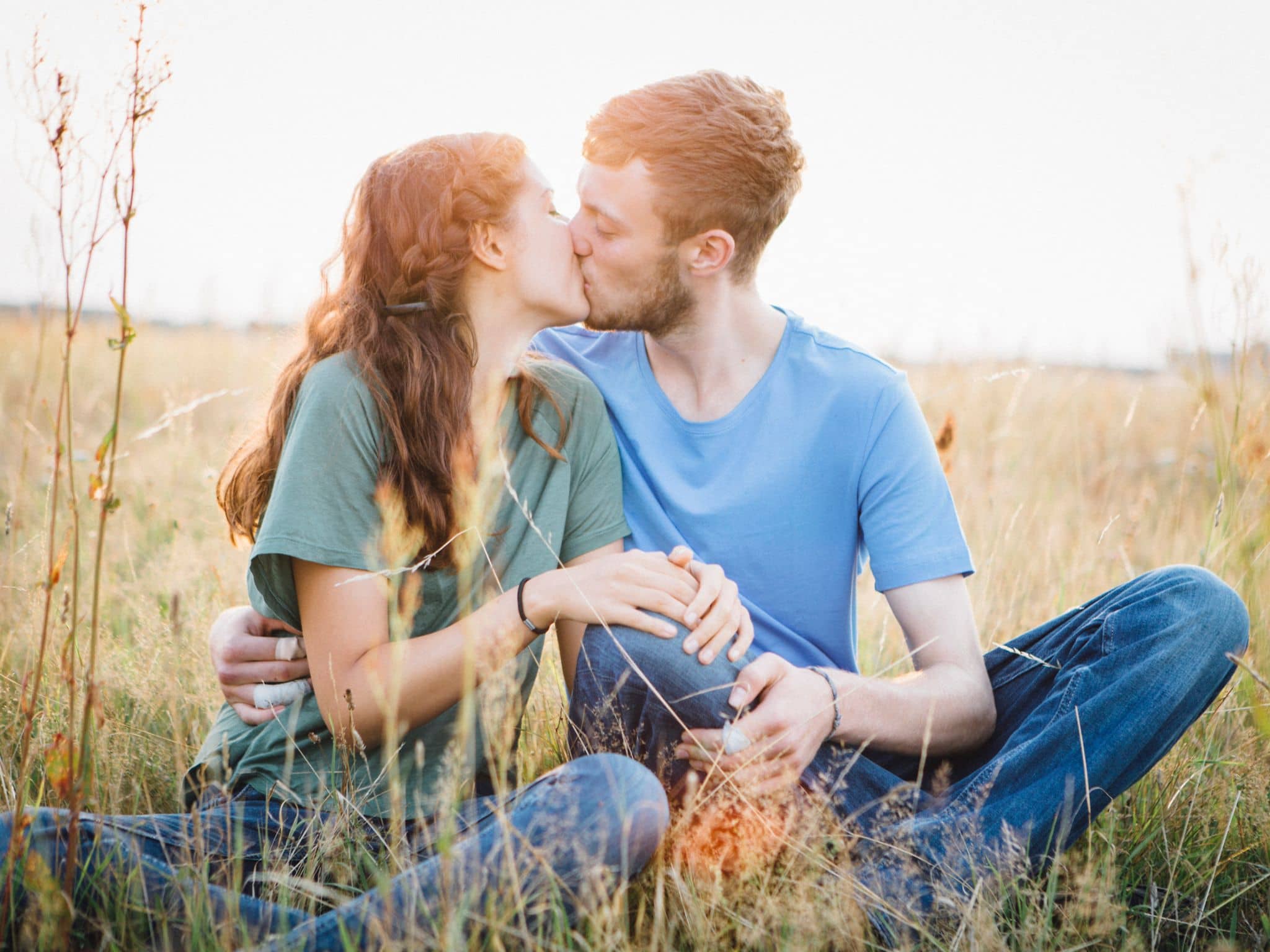 Ab wann bin ich bereit für Sex? Ein junges Mädchen und ein Jugendlicher sitzen auf einer Wiese uns küssen sich