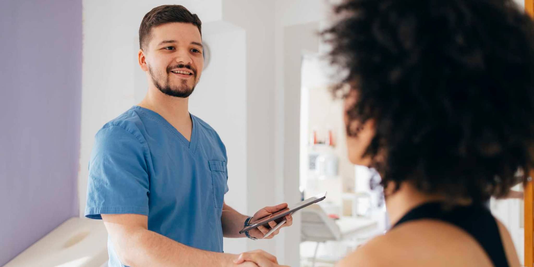 Bild: Physiotherapeut begrüßt eine Patientin.